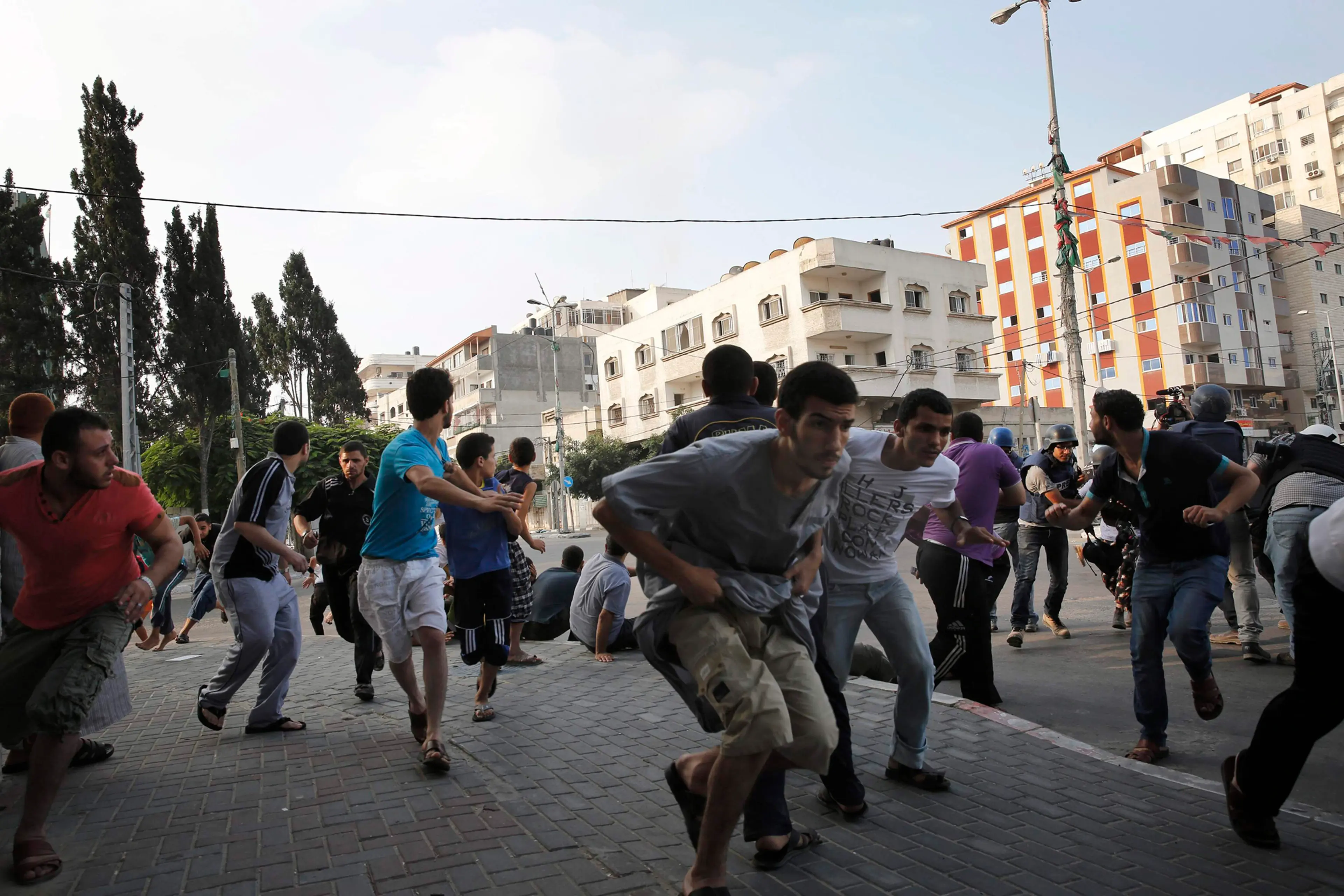 Palestinians take cover as warning Israeli air strikes are fired at a nearby building in Gaza City, July 22, 2014.