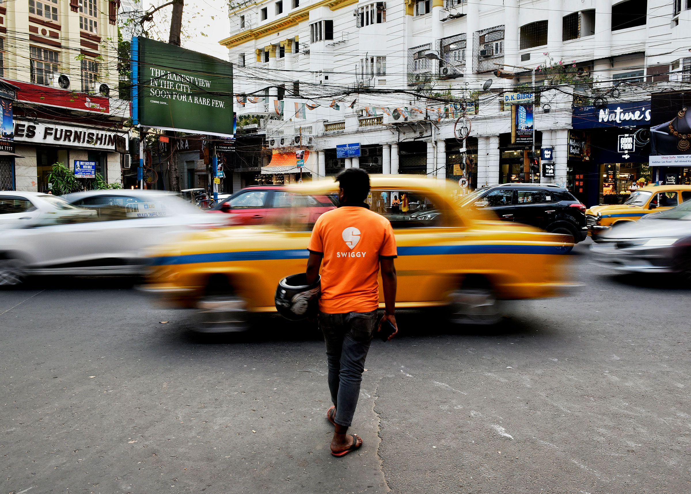A Swiggy delivery worker crosses a road in Kolkata, India, March 22, 2022.
