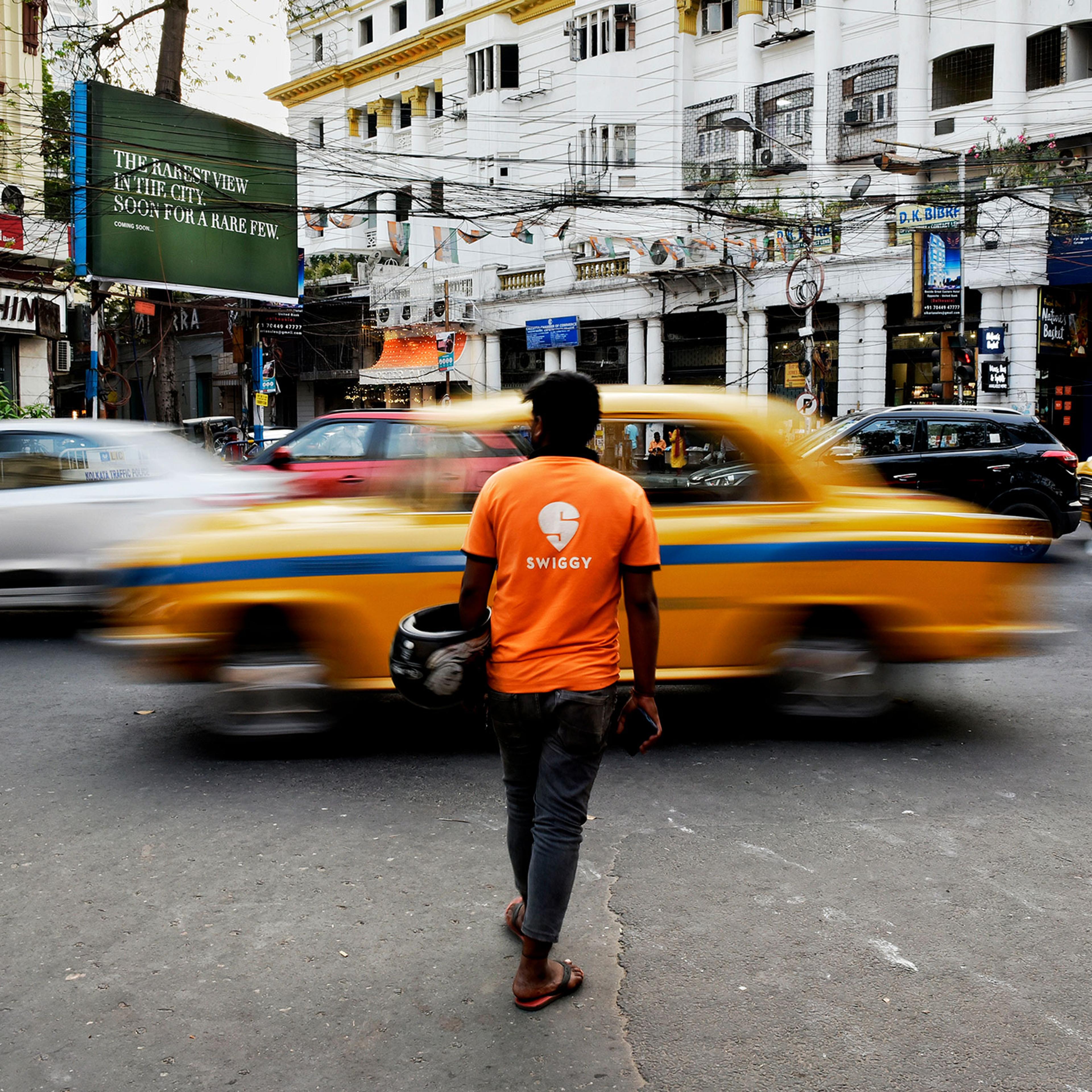 A Swiggy delivery worker crosses a road in Kolkata, India, March 22, 2022.