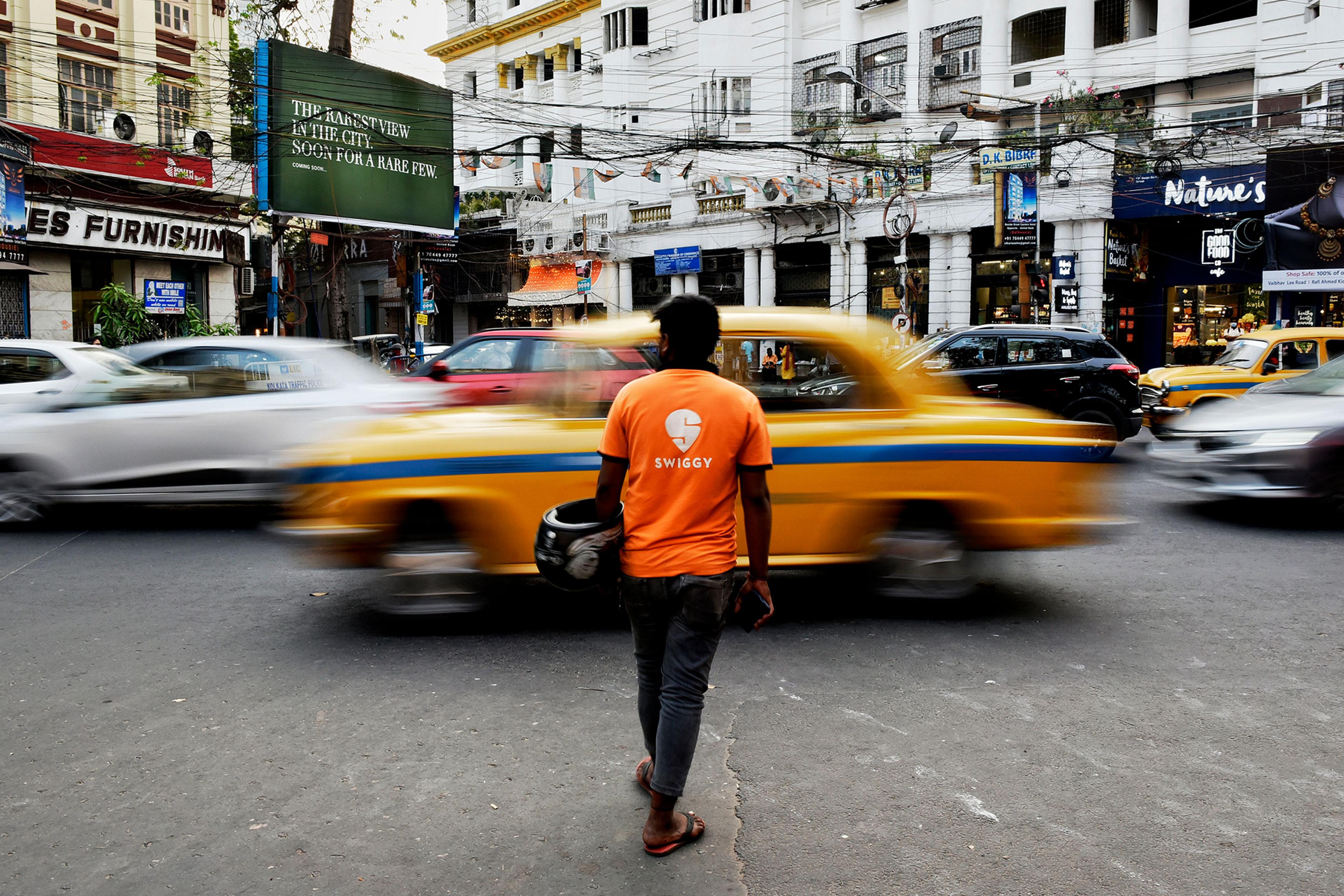 A Swiggy delivery worker crosses a road in Kolkata, India, March 22, 2022.