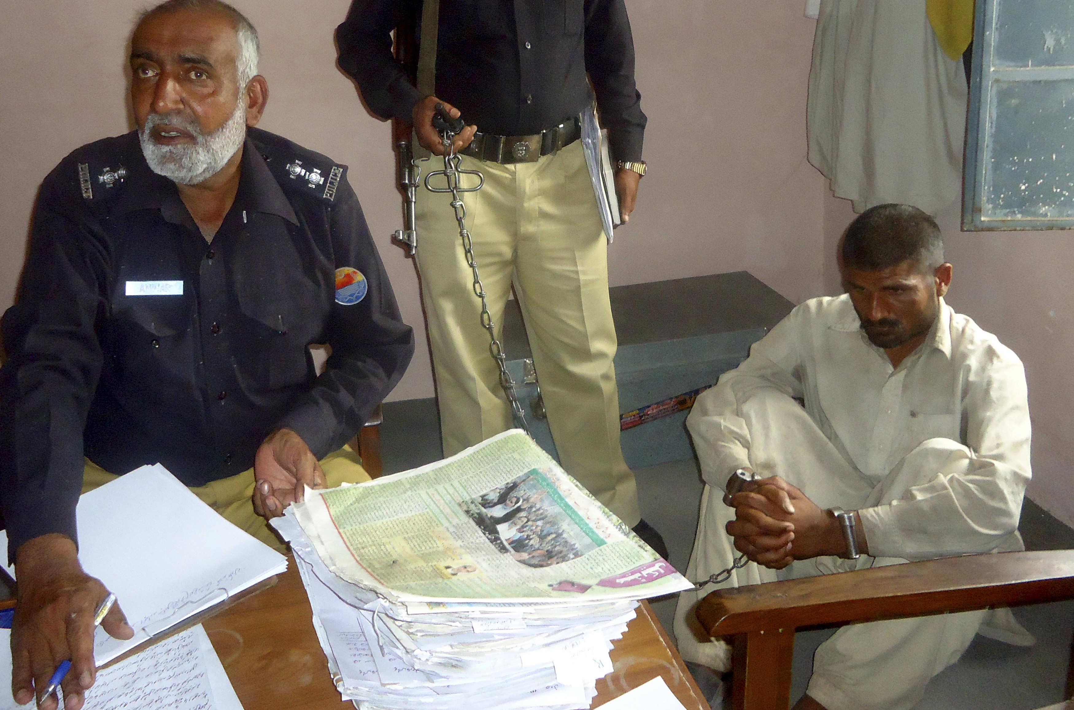 Mohammad Arif sits in a police custody at a police station, in the town of Darya Khan