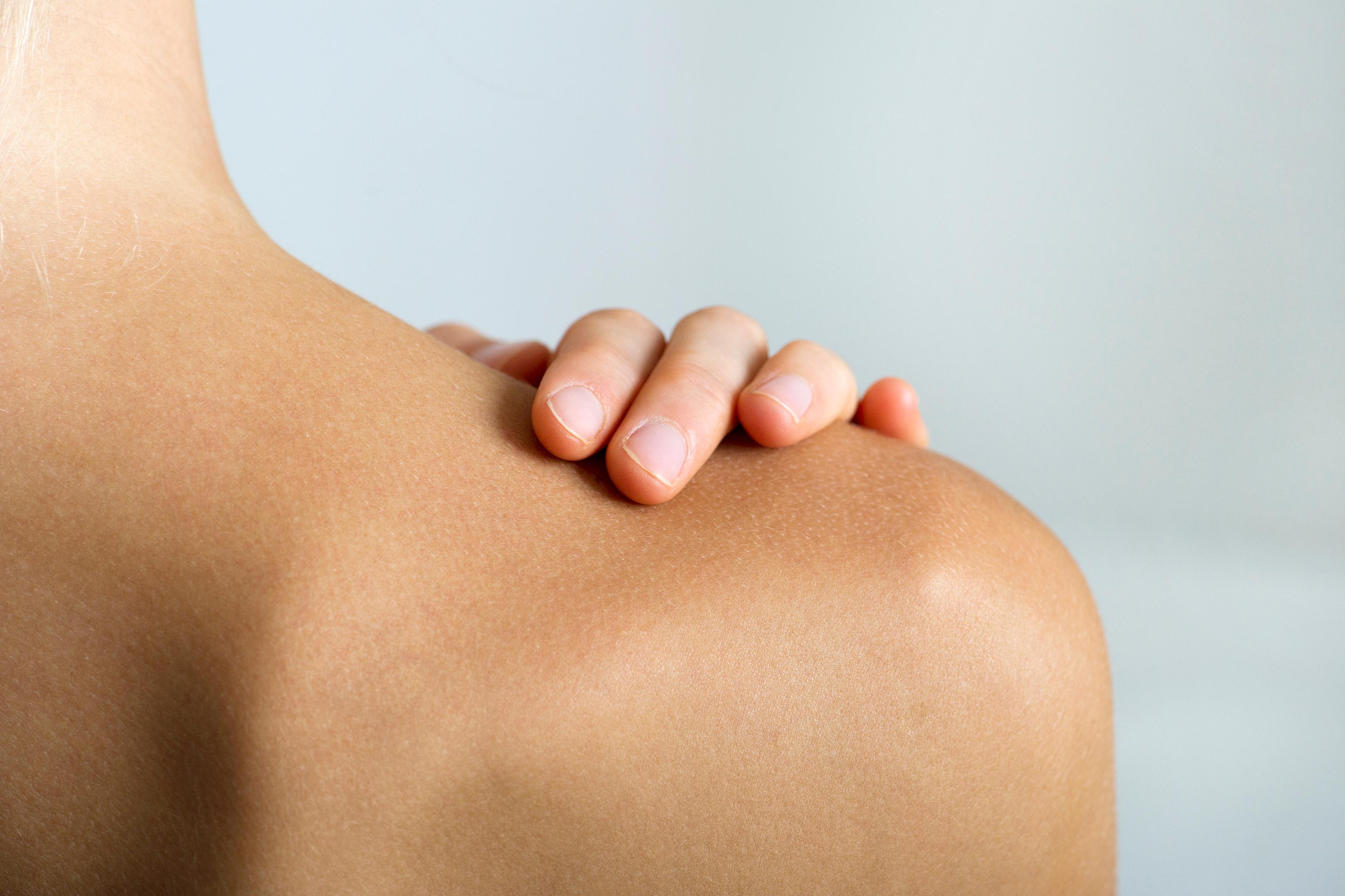 Woman with hand on bare shoulder, close-up TIME health stock