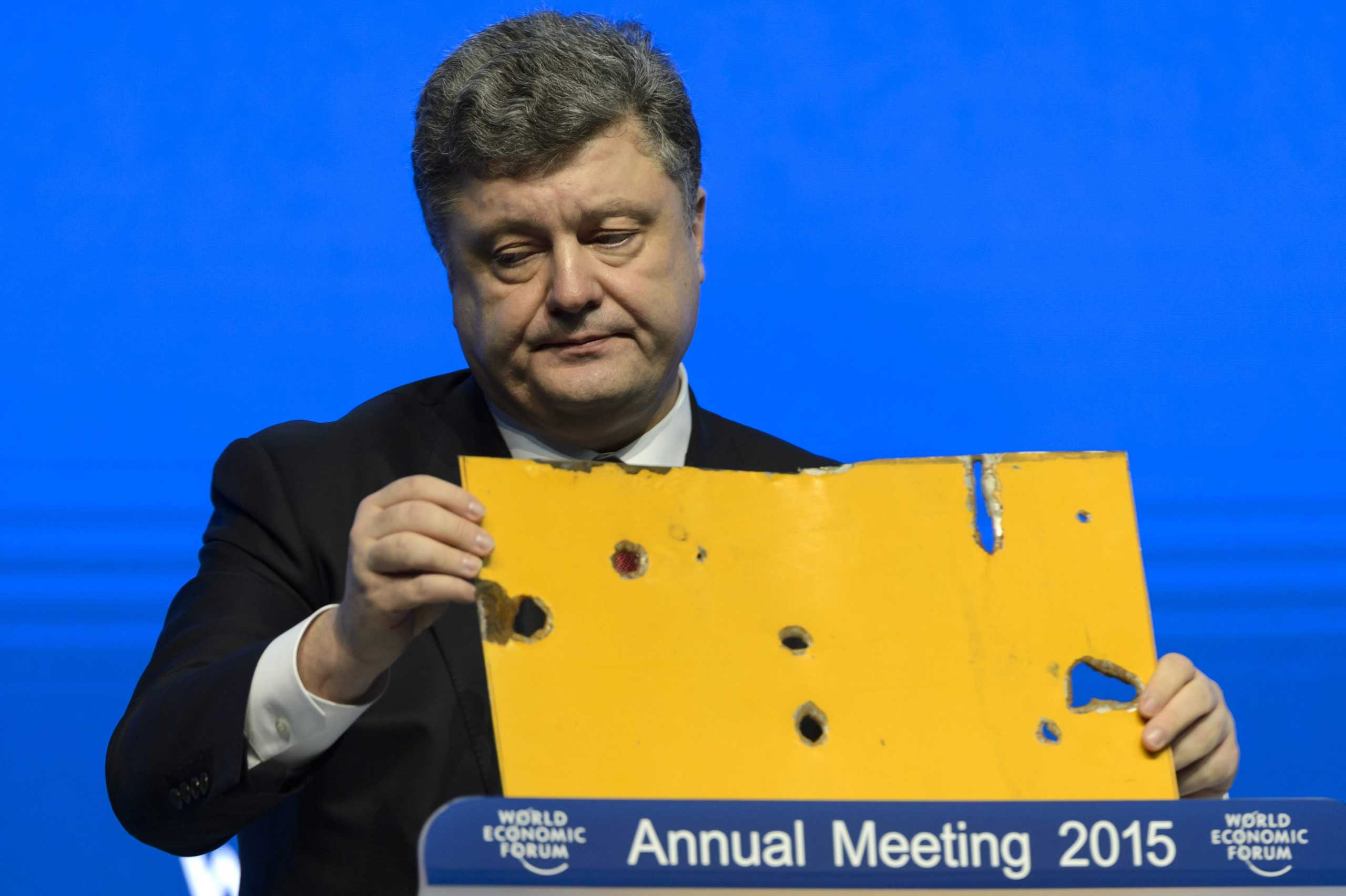 The president of Ukraine Petro Poroshenko speaks with a piece of a damaged passenger bus hit by a shell that killed twelve passengers and injured 13 others at a Ukrainian military checkpoint near the town of Volnovakha, during a panel session on the firs