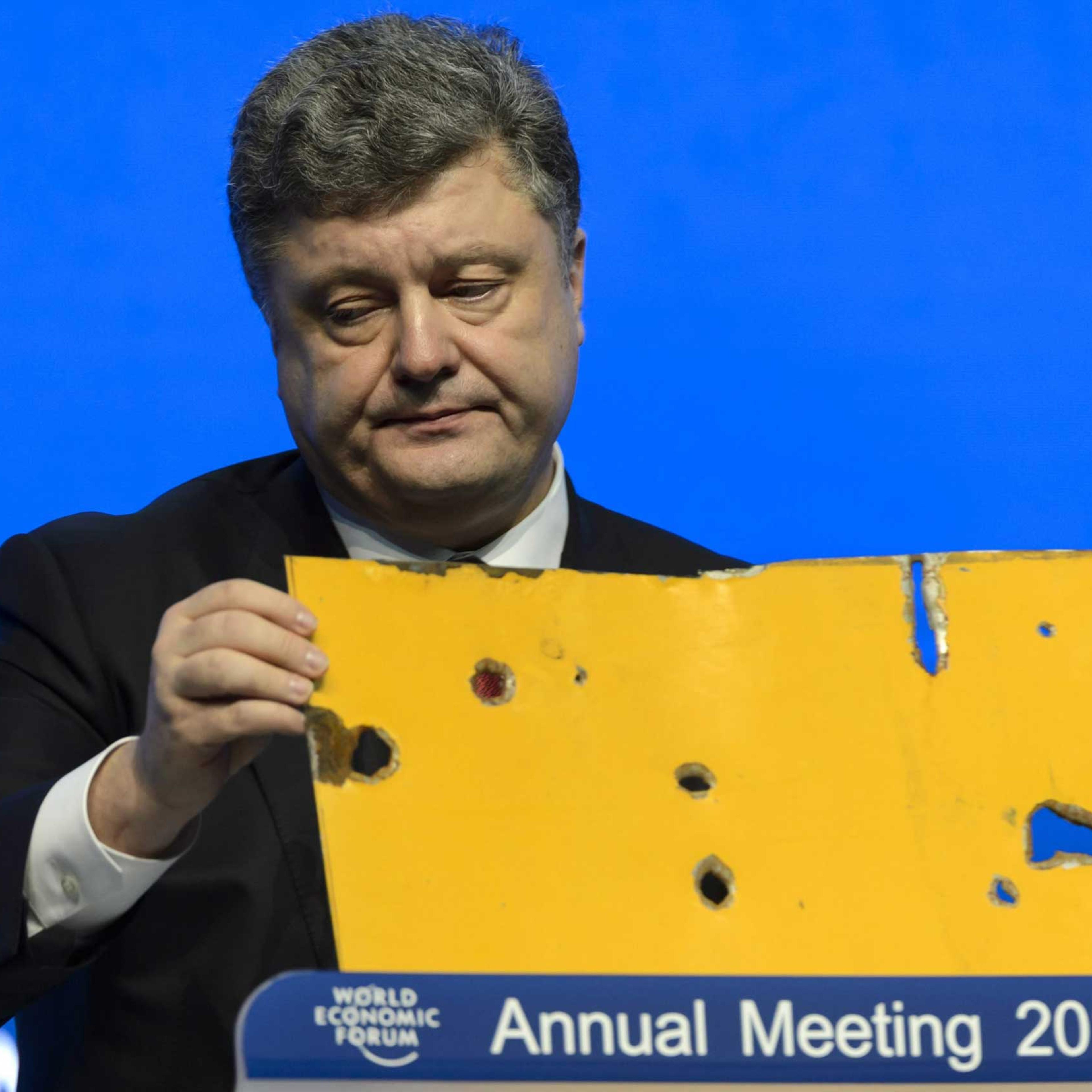 The president of Ukraine Petro Poroshenko speaks with a piece of a damaged passenger bus hit by a shell that killed twelve passengers and injured 13 others at a Ukrainian military checkpoint near the town of Volnovakha, during a panel session on the firs