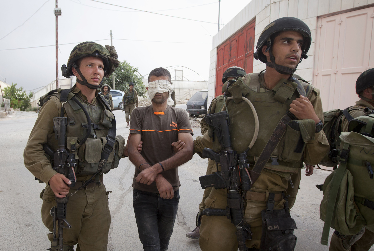 Israeli soldiers arrest a Palestinian man during a search for three missing Israeli teens, feared abducted in the West Bank last week, in the village of Beit Kahil near the West Bank city of Hebron on June 21, 2014.