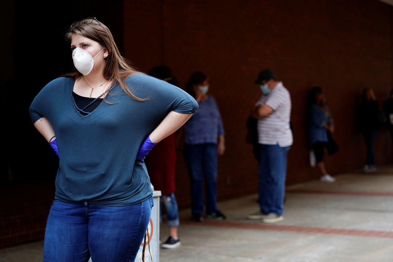 A woman who lost her job waits in line to file for unemployment following an outbreak of the coronavirus, at an Arkansas Workforce Center in Fort Smith, Ark., April 6, 2020. 
