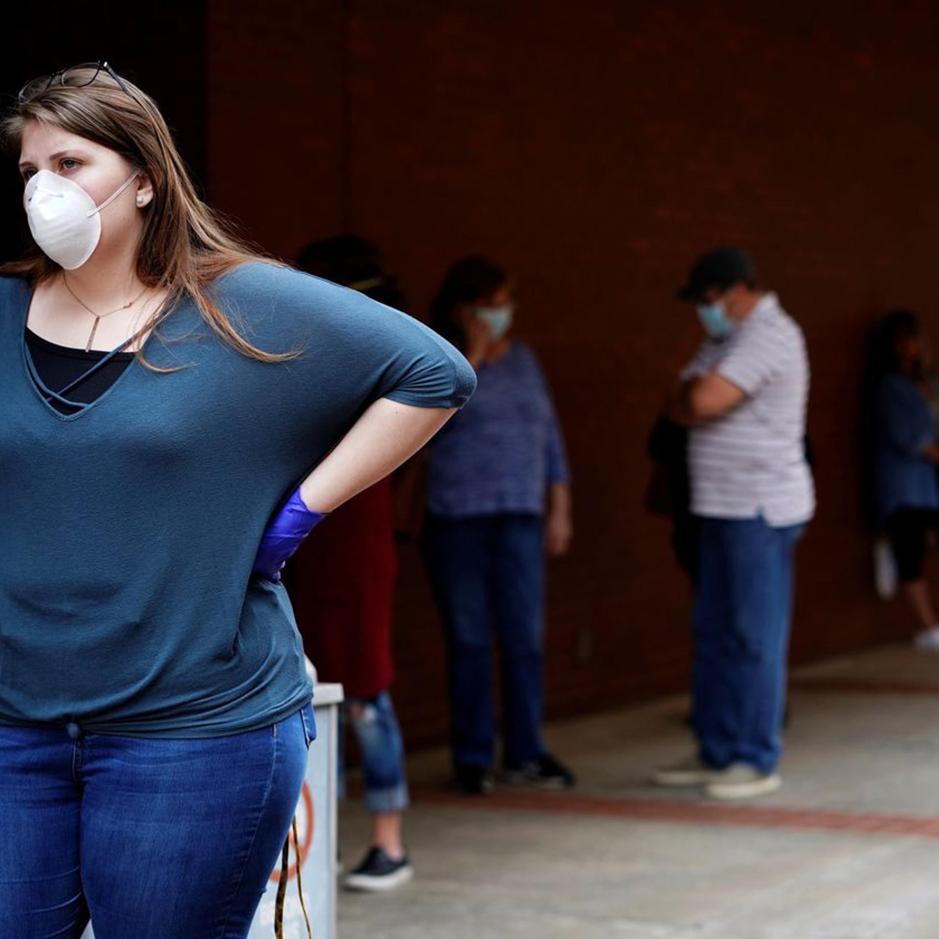 A woman who lost her job waits in line to file for unemployment following an outbreak of the coronavirus, at an Arkansas Workforce Center in Fort Smith, Ark., April 6, 2020.