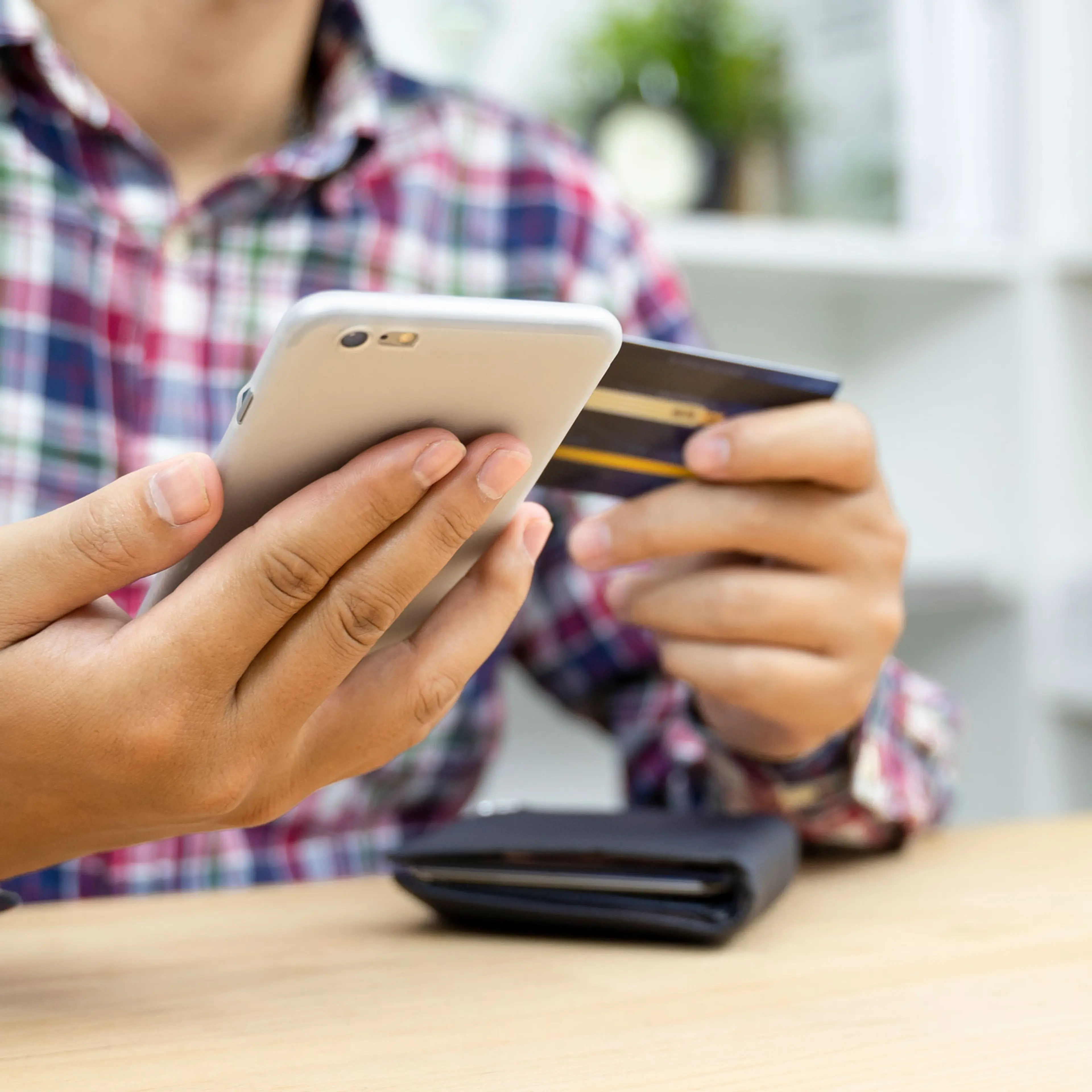 Young man hands holding credit card and using phone