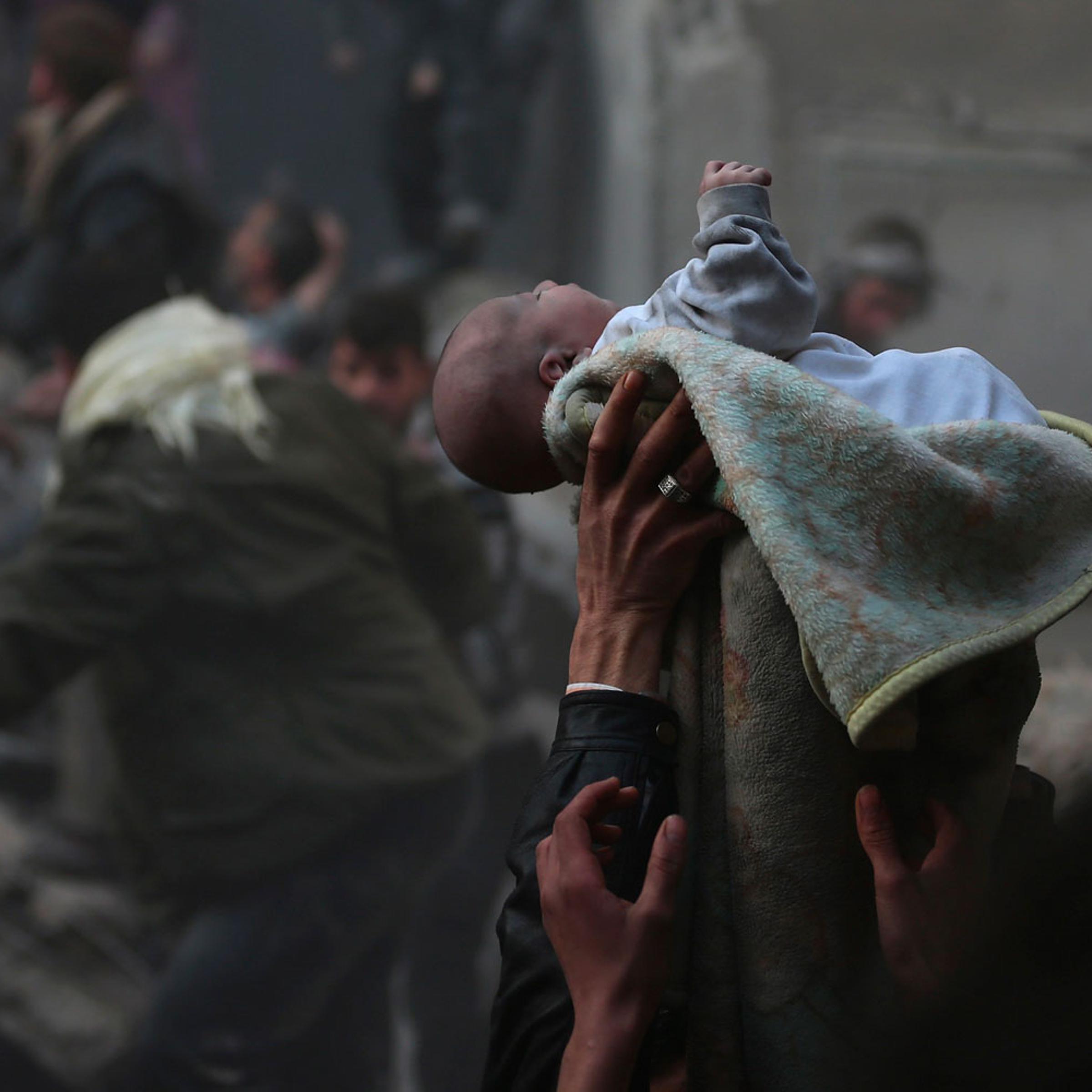 Men hold up a baby saved from what activists say was an airstrike by forces loyal to Syrian President Bashar al-Assad in Damascus on January 7, 2014.