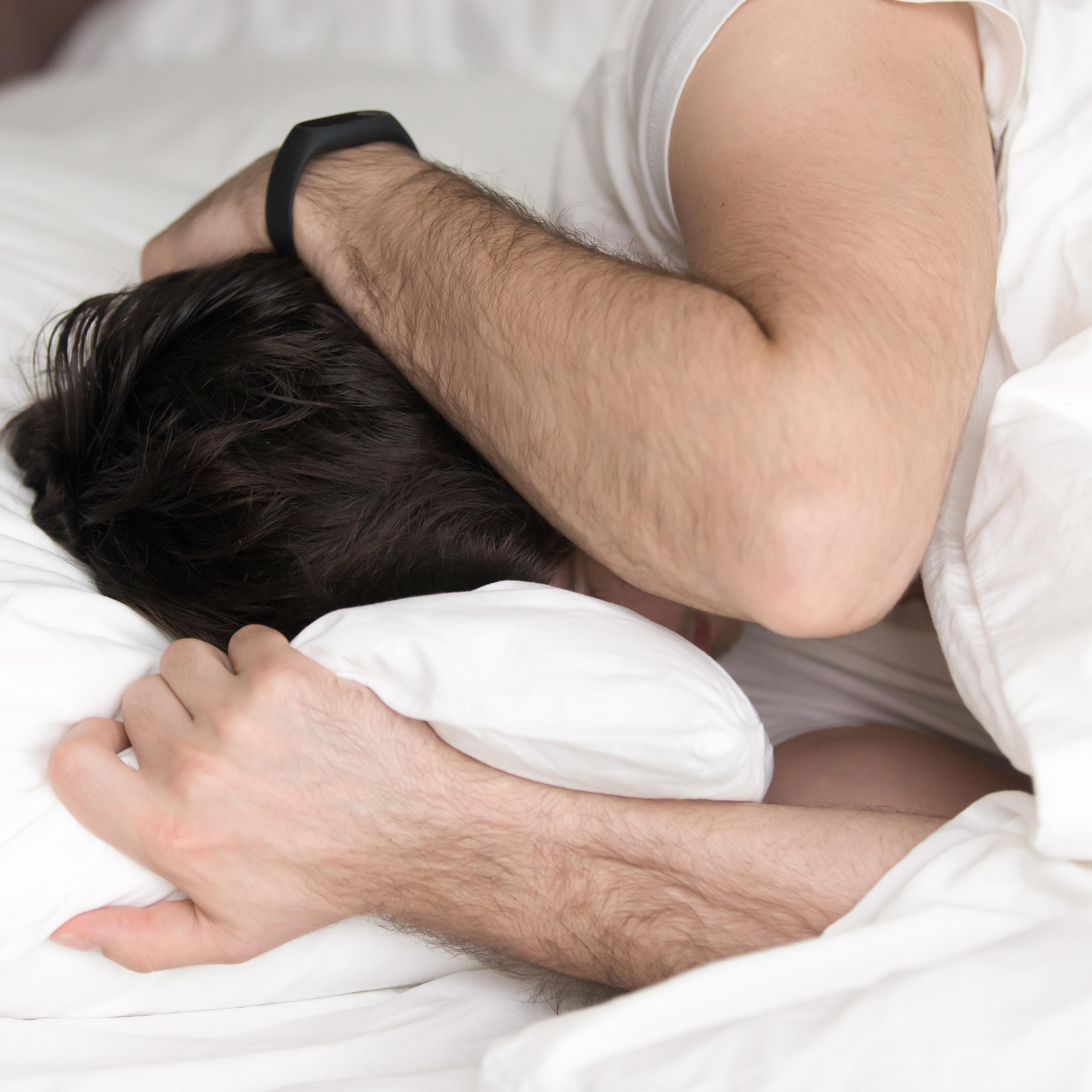 Man covering head with hands in bed, wakeup or depression