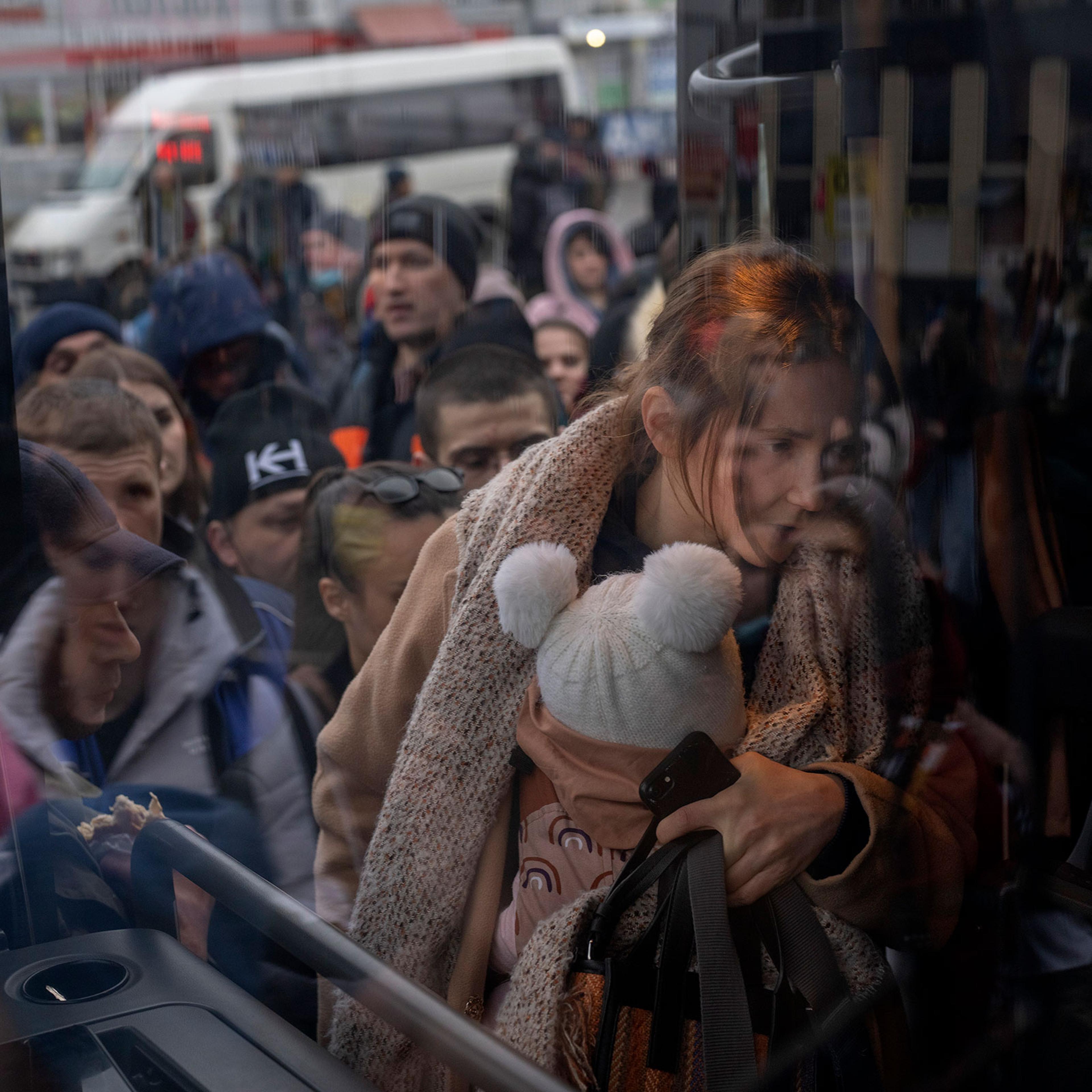 A woman holds her baby as she gets on a bus leaving Kyiv on Feb. 24.