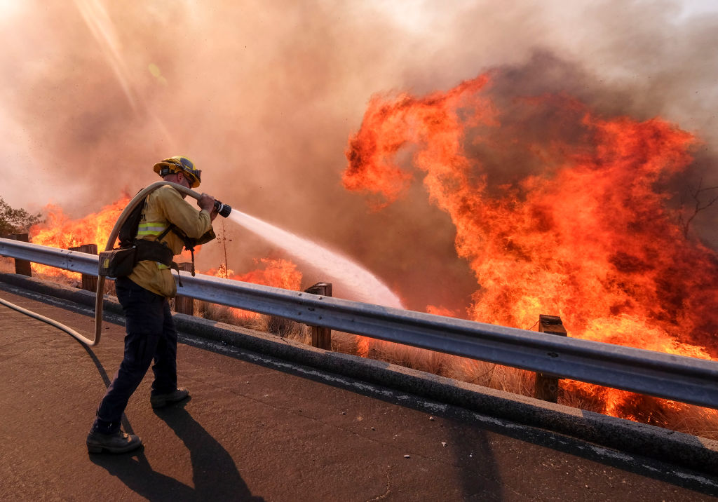 A firefighter battles wildfire near a freeway in Simi Valley, California