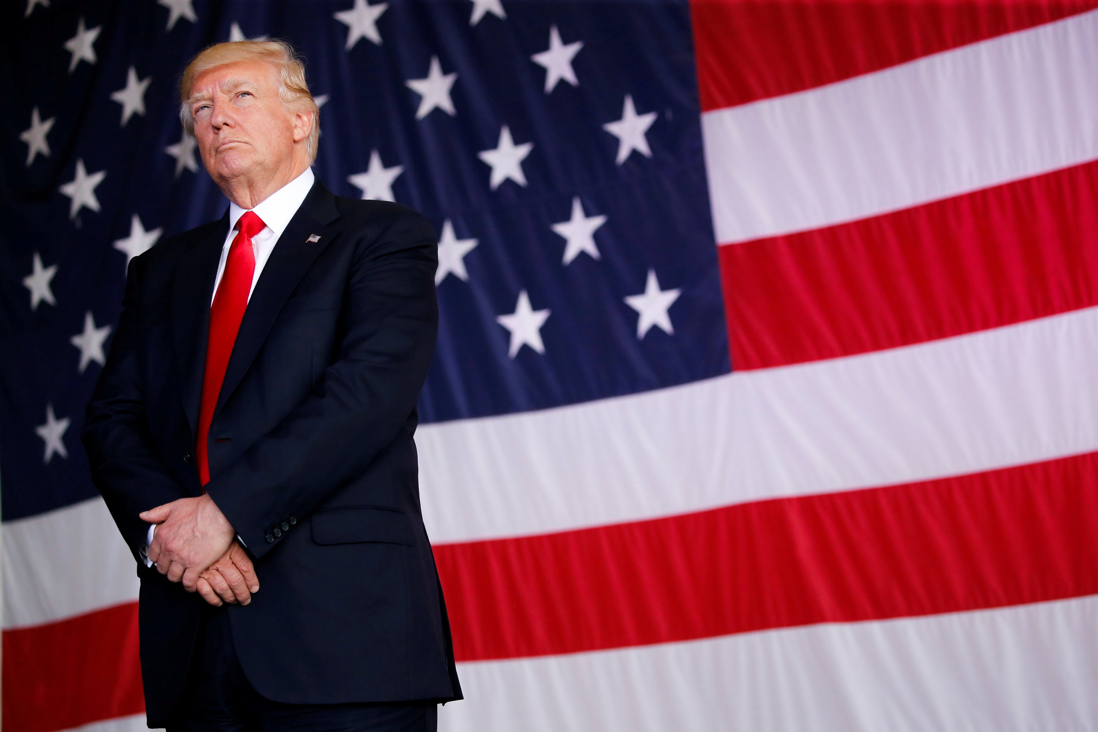 FILE PHOTO: U.S. President Trump stands in front of a U.S. flag while listening to U.S. first lady Melania Trump give a speech to U.S. troops at the Naval Air Station Sigonella before returning to Washington D.C. at Sigonella Air Force Base in Sigonella