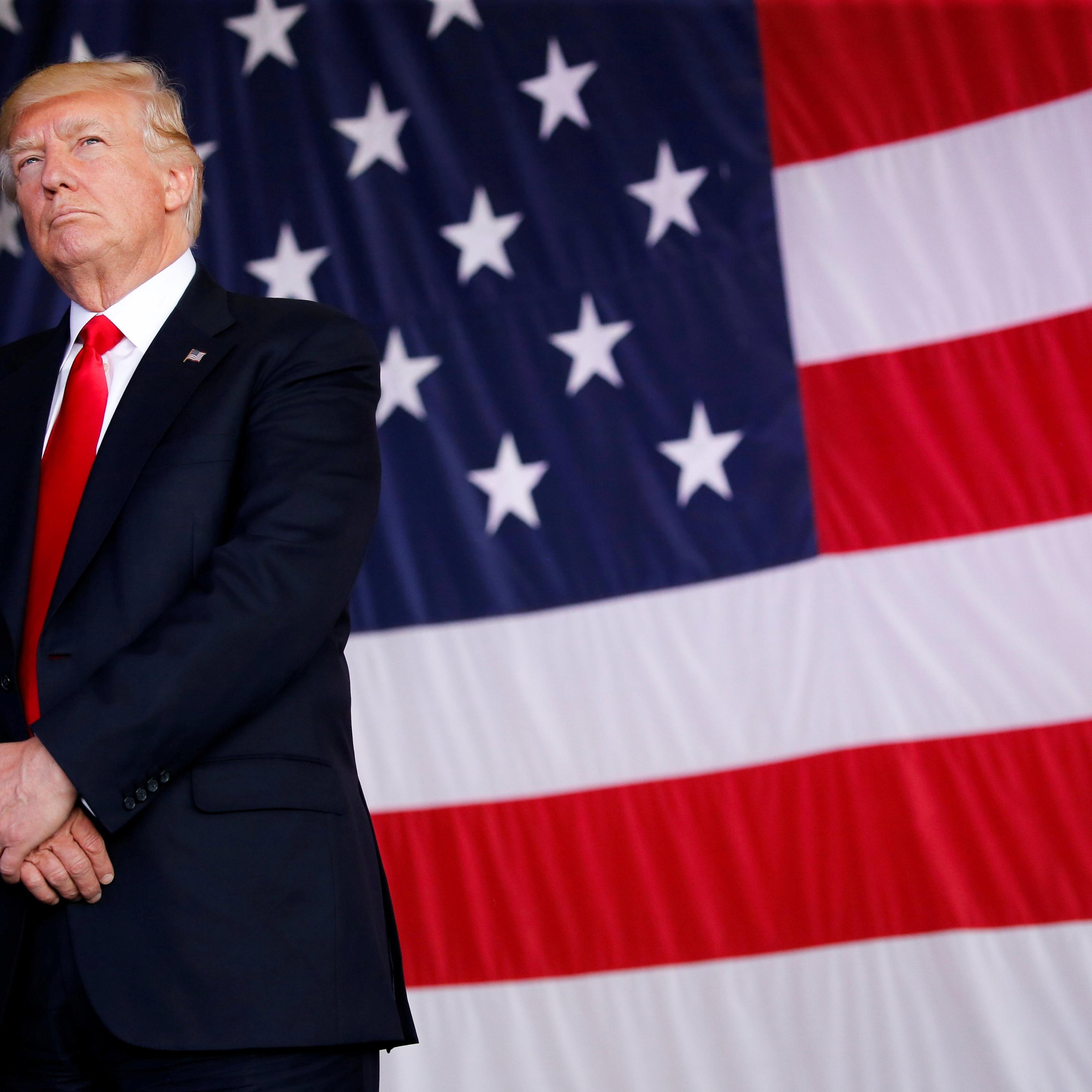 FILE PHOTO: U.S. President Trump stands in front of a U.S. flag while listening to U.S. first lady Melania Trump give a speech to U.S. troops at the Naval Air Station Sigonella before returning to Washington D.C. at Sigonella Air Force Base in Sigonella