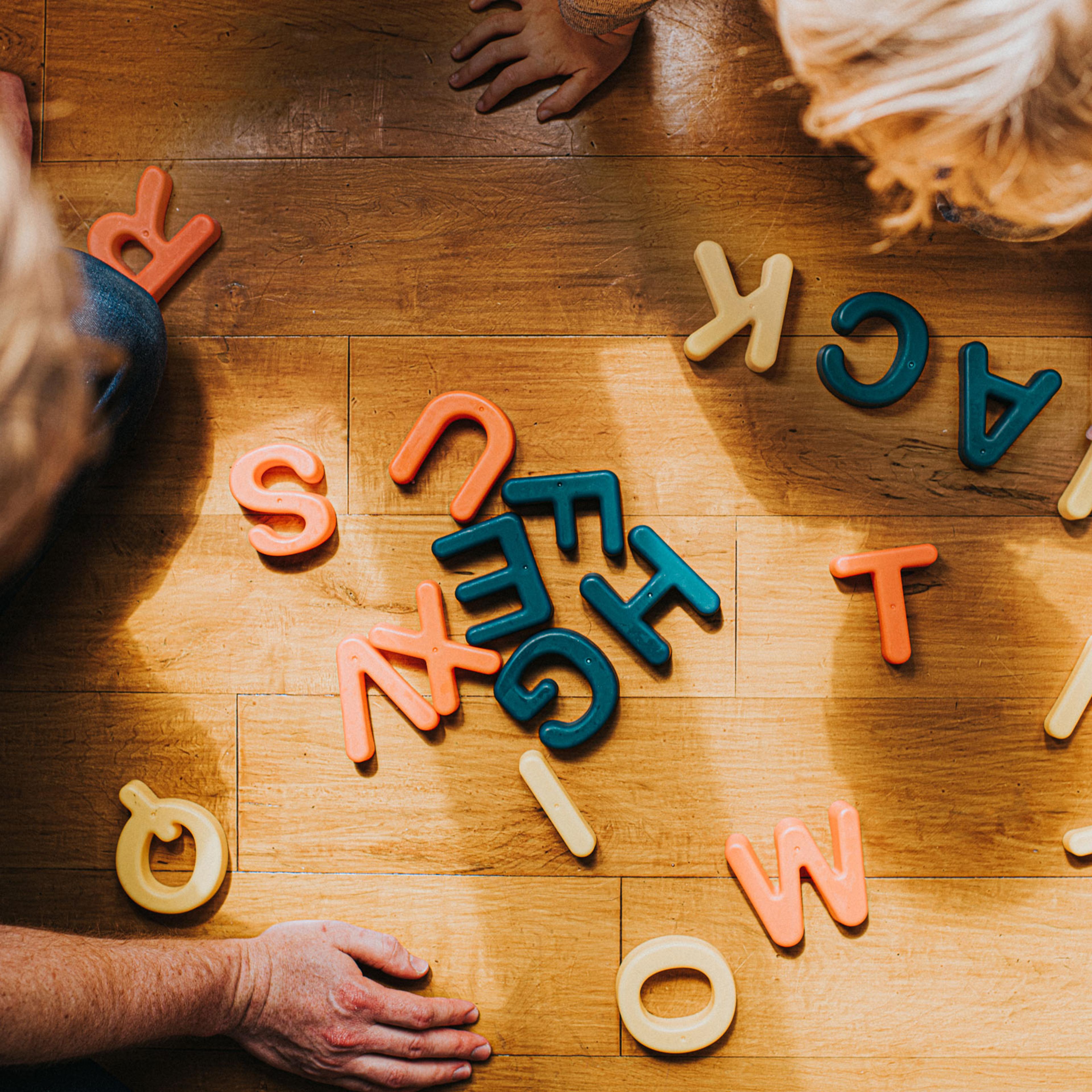 Child arranges colourful capital letters to create words