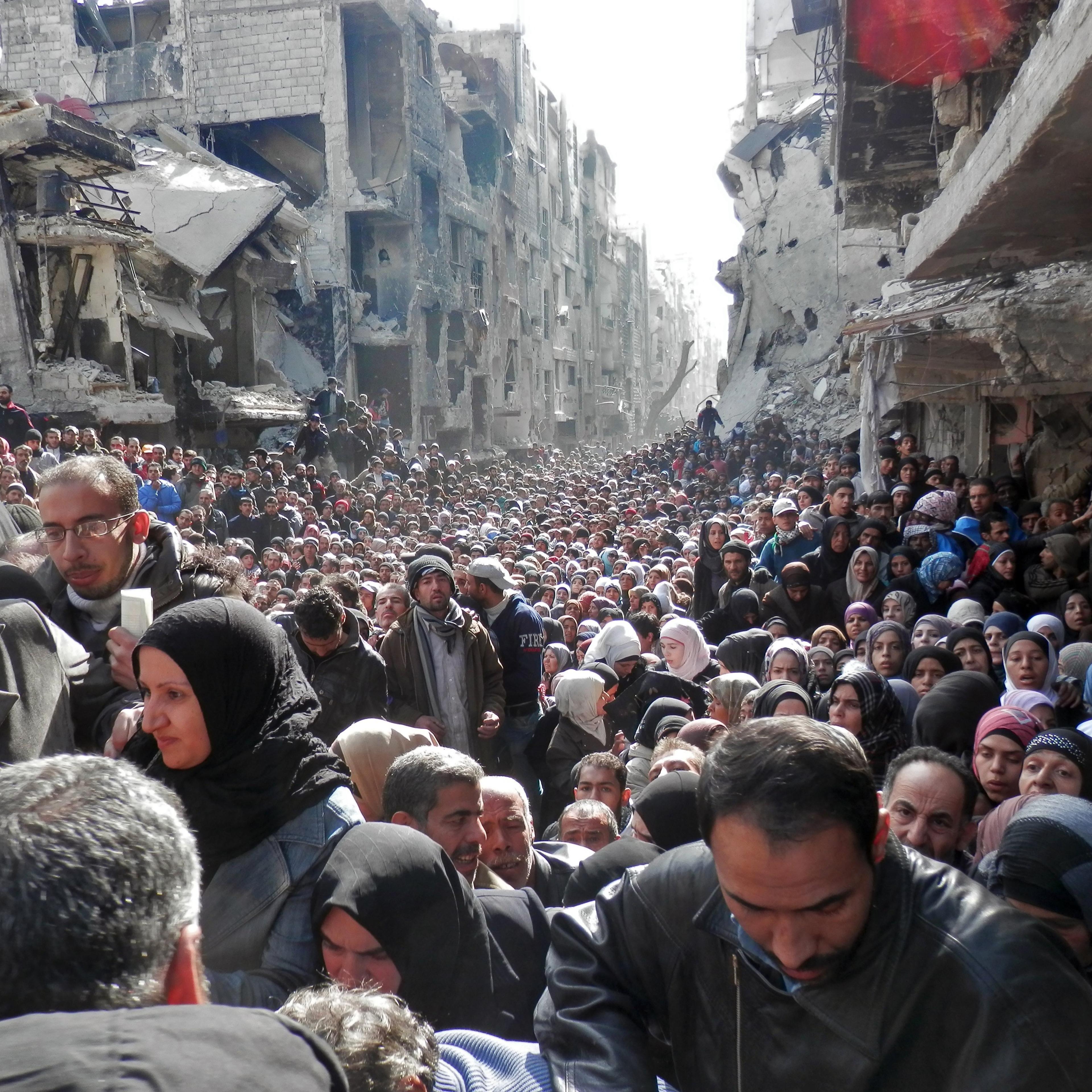 Residents wait in line to receive food aid distributed in the Yarmouk refugee camp on Jan. 31, 2014 in Damascus.