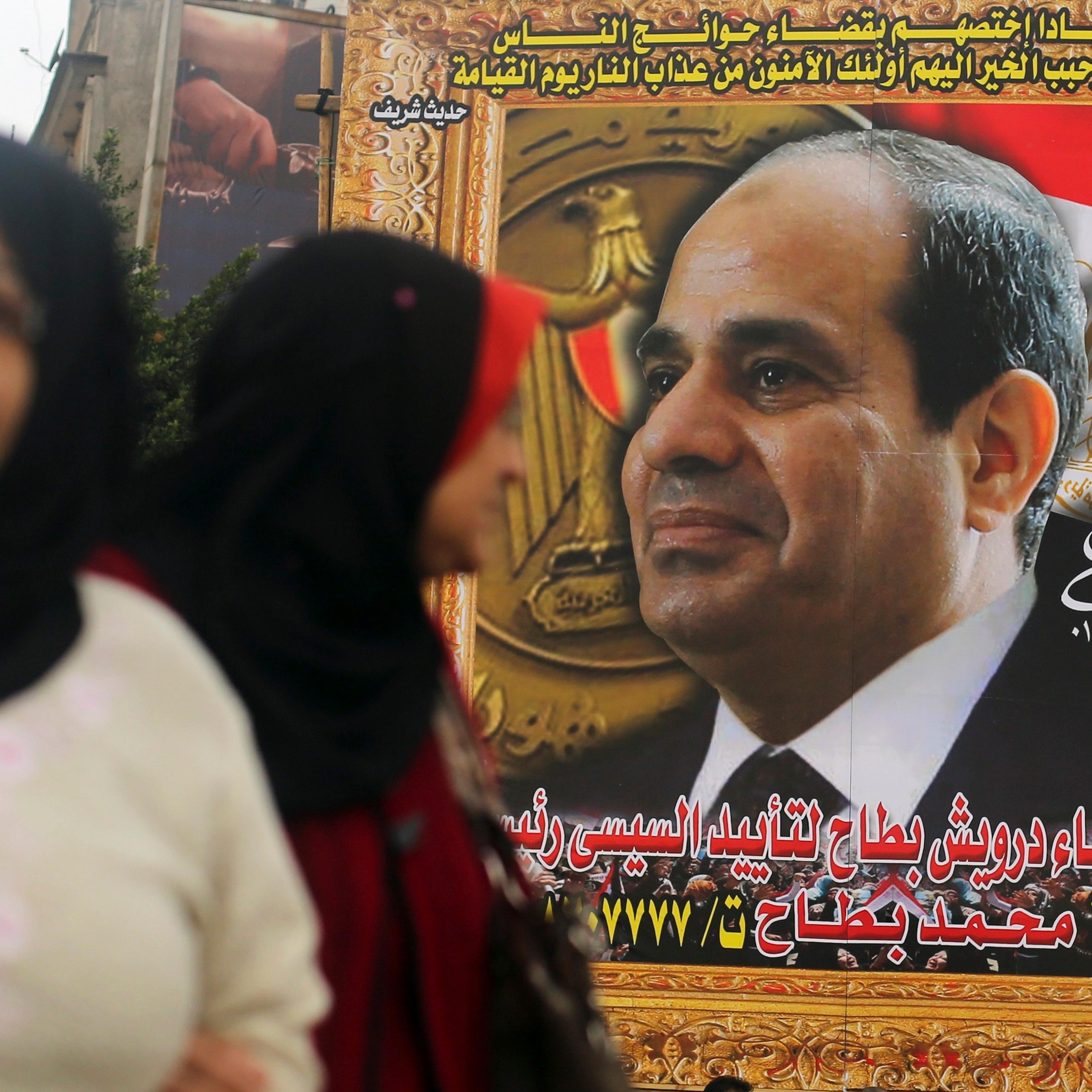 Women walk in front of huge banner for Egypt's army chief, al-Sisi in downtown Cairo
