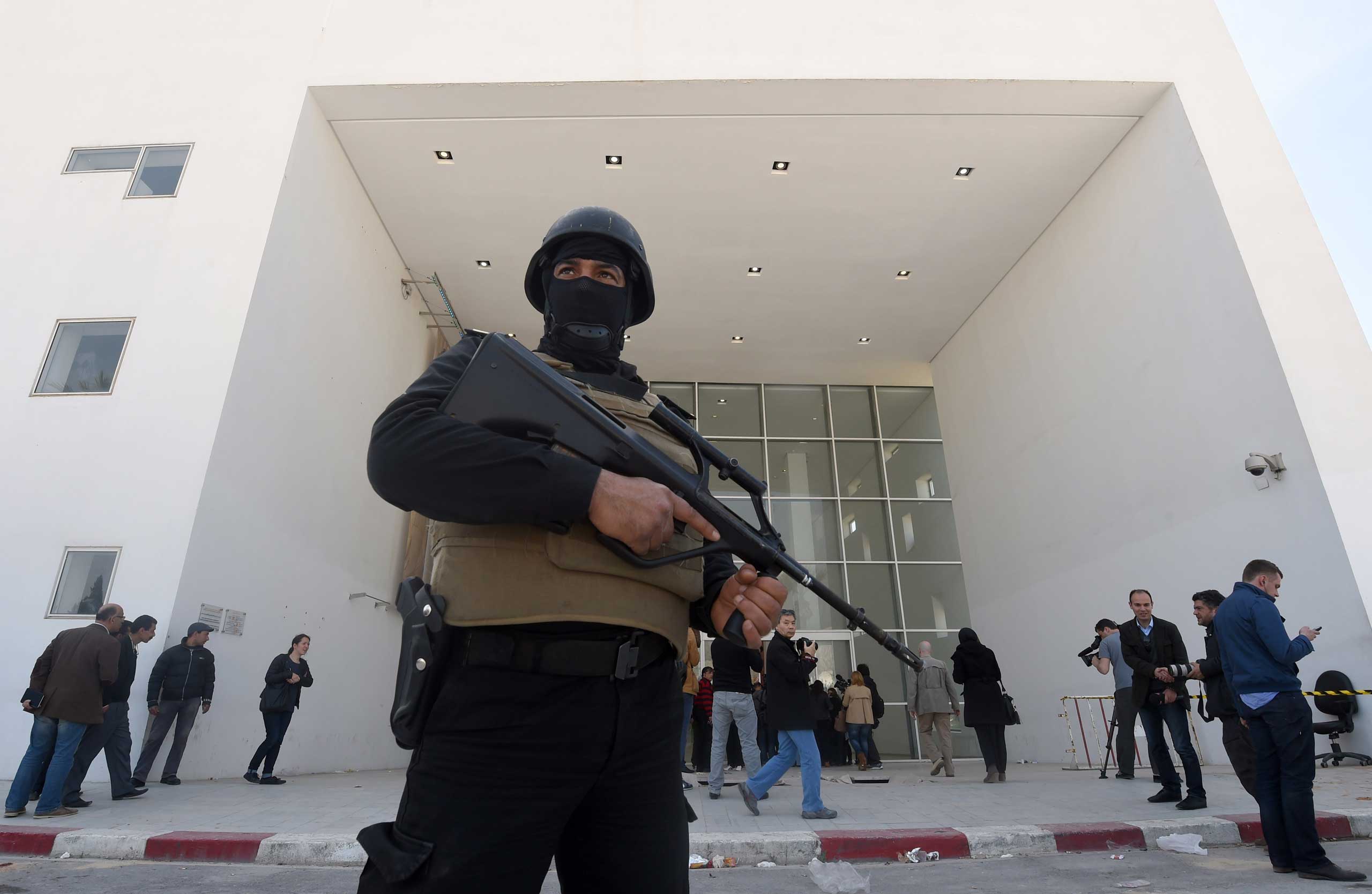 A member of the Tunisian security forces stands guard as journalists gather at the visitors entrance of the National Bardo Museum in Tunis on March 19, 2015.