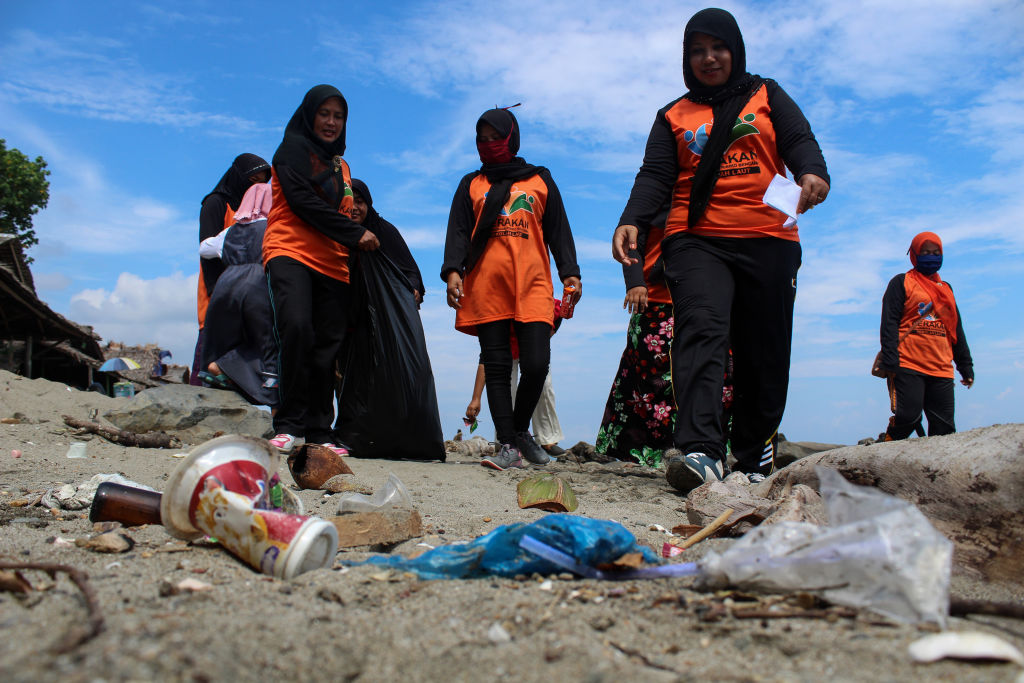 Volunteers seen holding a plastic bag to pick up garbage on