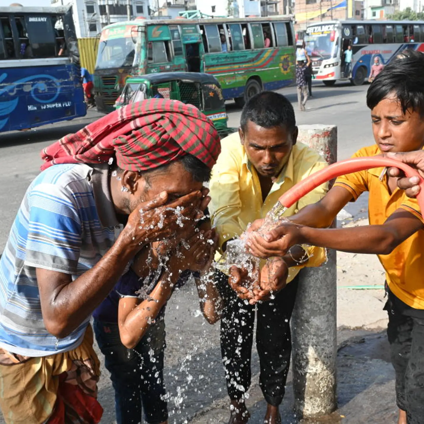Three people drink water and wash their faces to try to cool off during a heat wave in Bangaldesh.