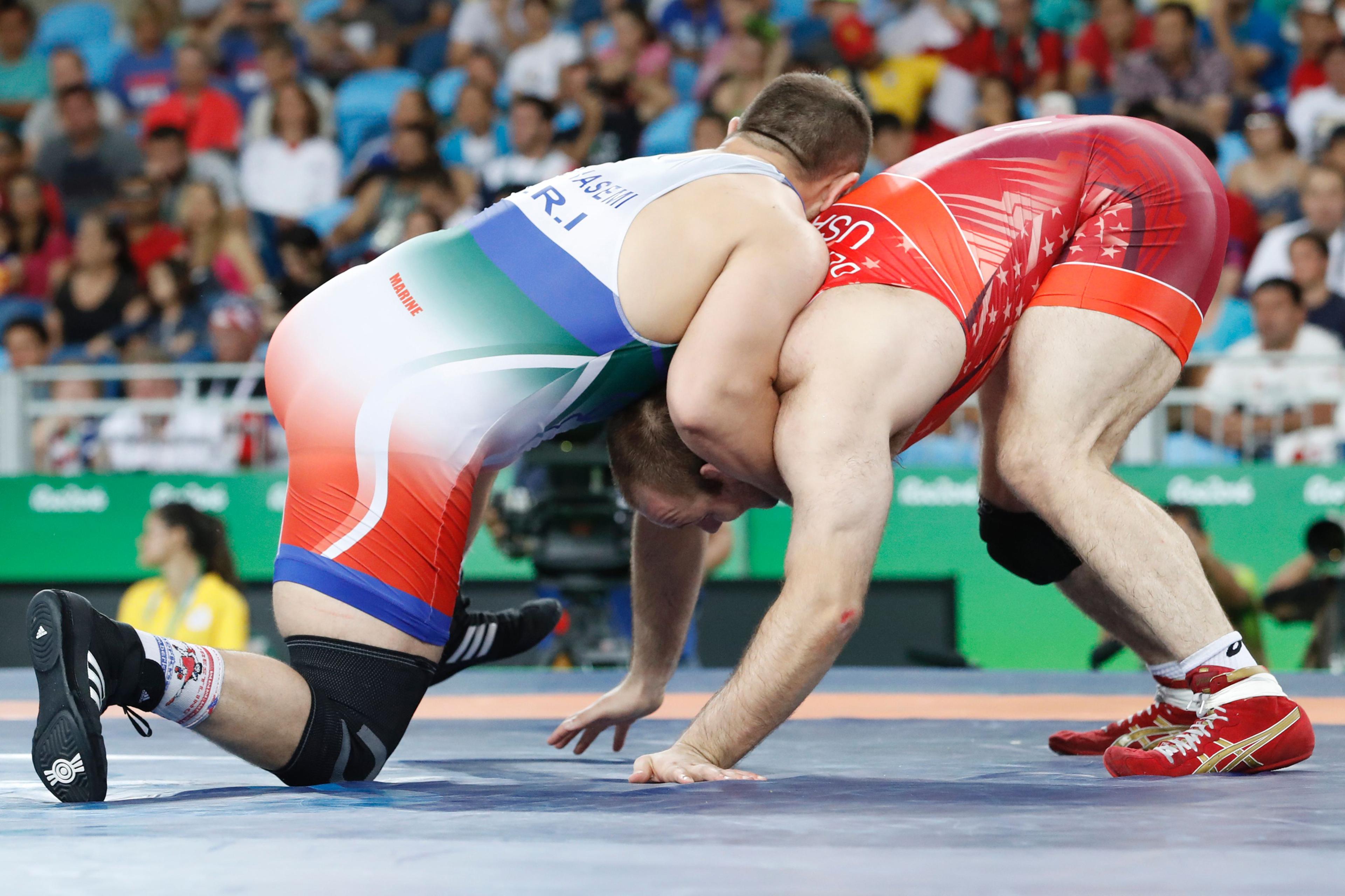 Iran's Komeil Nemat Ghasemi (blue) wrestles with USA's Tervel Ivaylov Dlagnev in their men's 125kg freestyle semi-final match on August 20, 2016, during the wrestling event of the Rio 2016 Olympic Games at the Carioca Arena 2 in Rio de Janeiro. / AFP / J