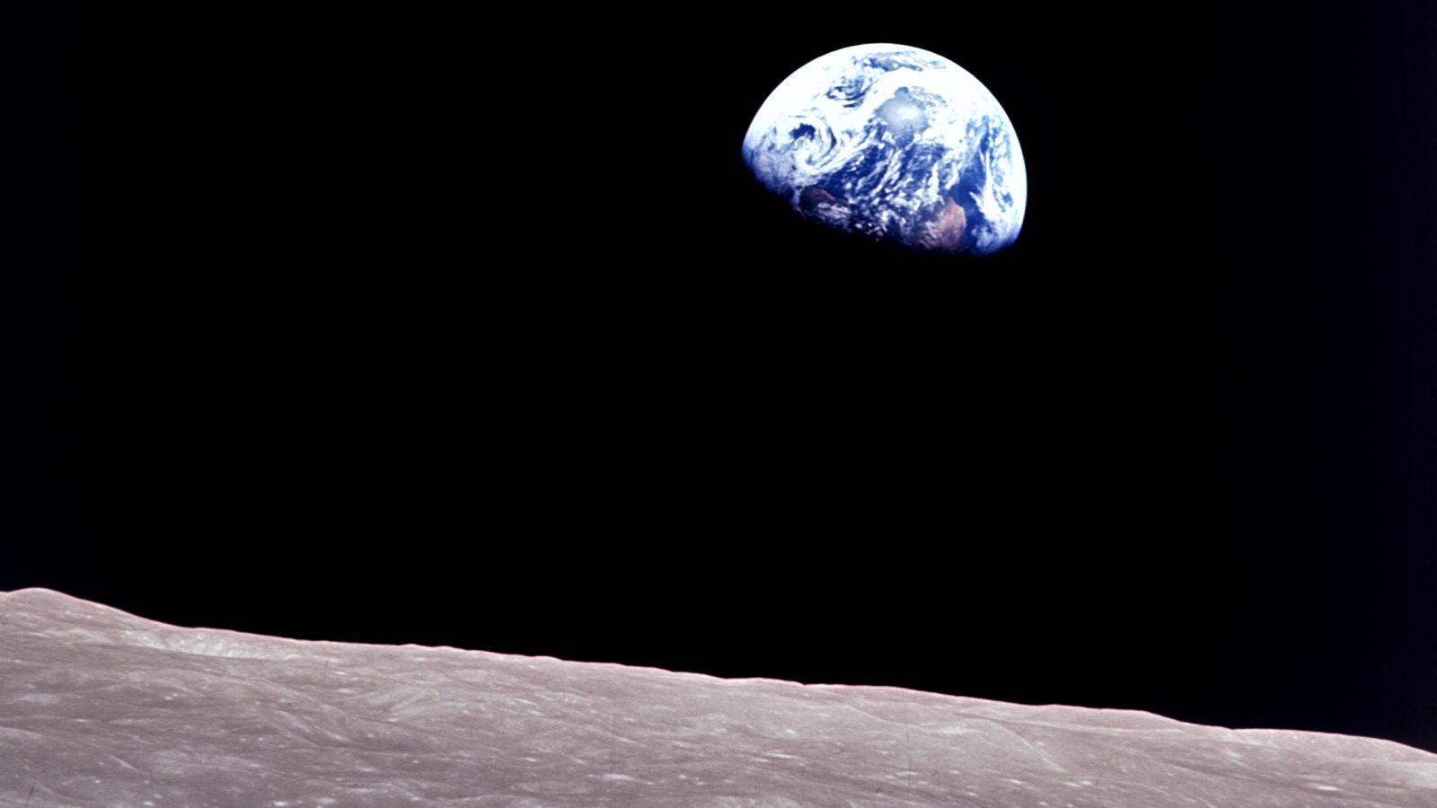 Taken aboard Apollo 8 by Bill Anders, this iconic picture shows Earth peeking out from beyond the lunar surface as the first crewed spacecraft circumnavigated the moon, with astronauts Anders, Frank Borman, and Jim Lovell aboard.