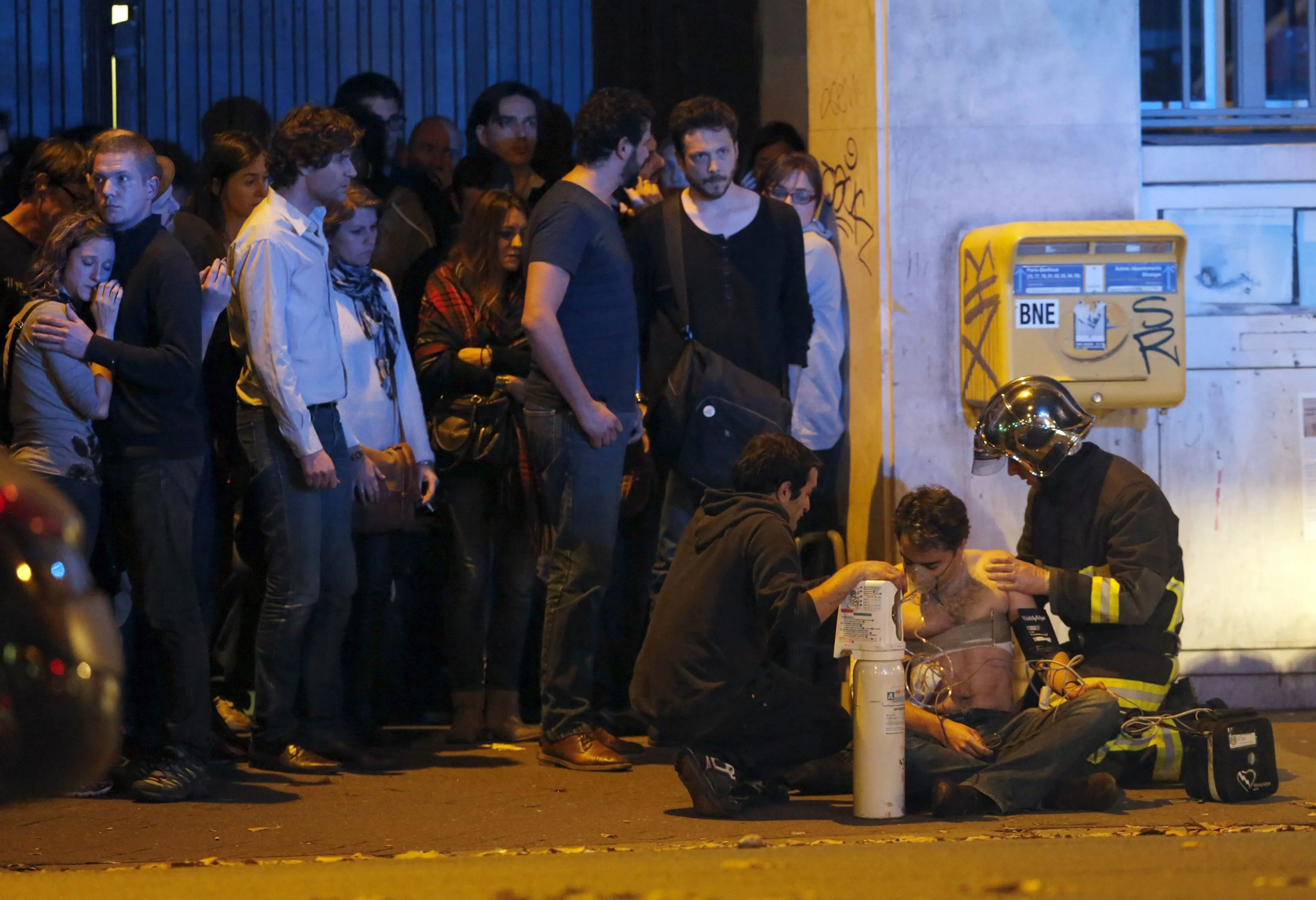 A member of the French fire brigade aids an injured individual near the Bataclan concert hall following fatal shootings in Paris on Nov. 13, 2015.