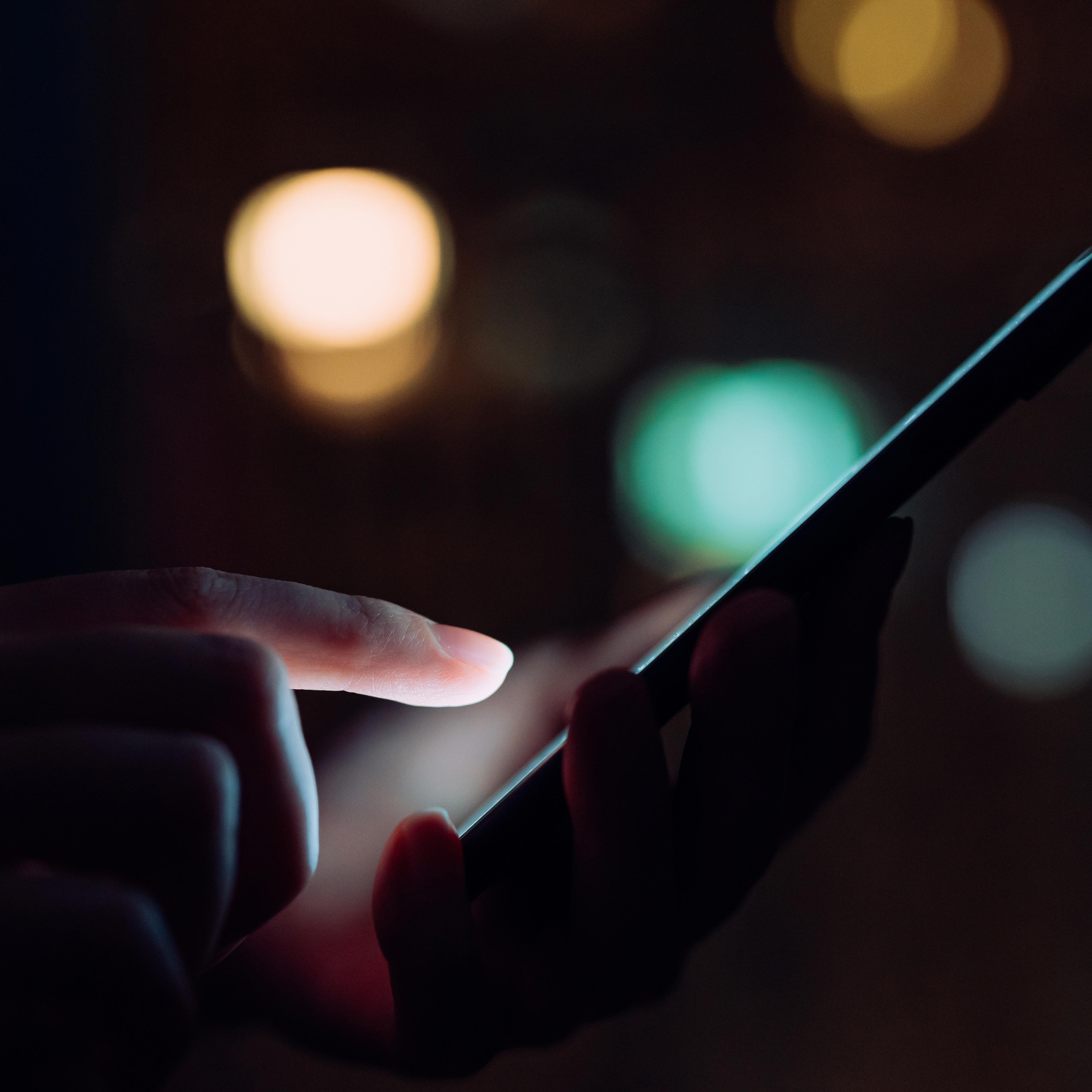 Close up of woman's hand using smartphone in the dark