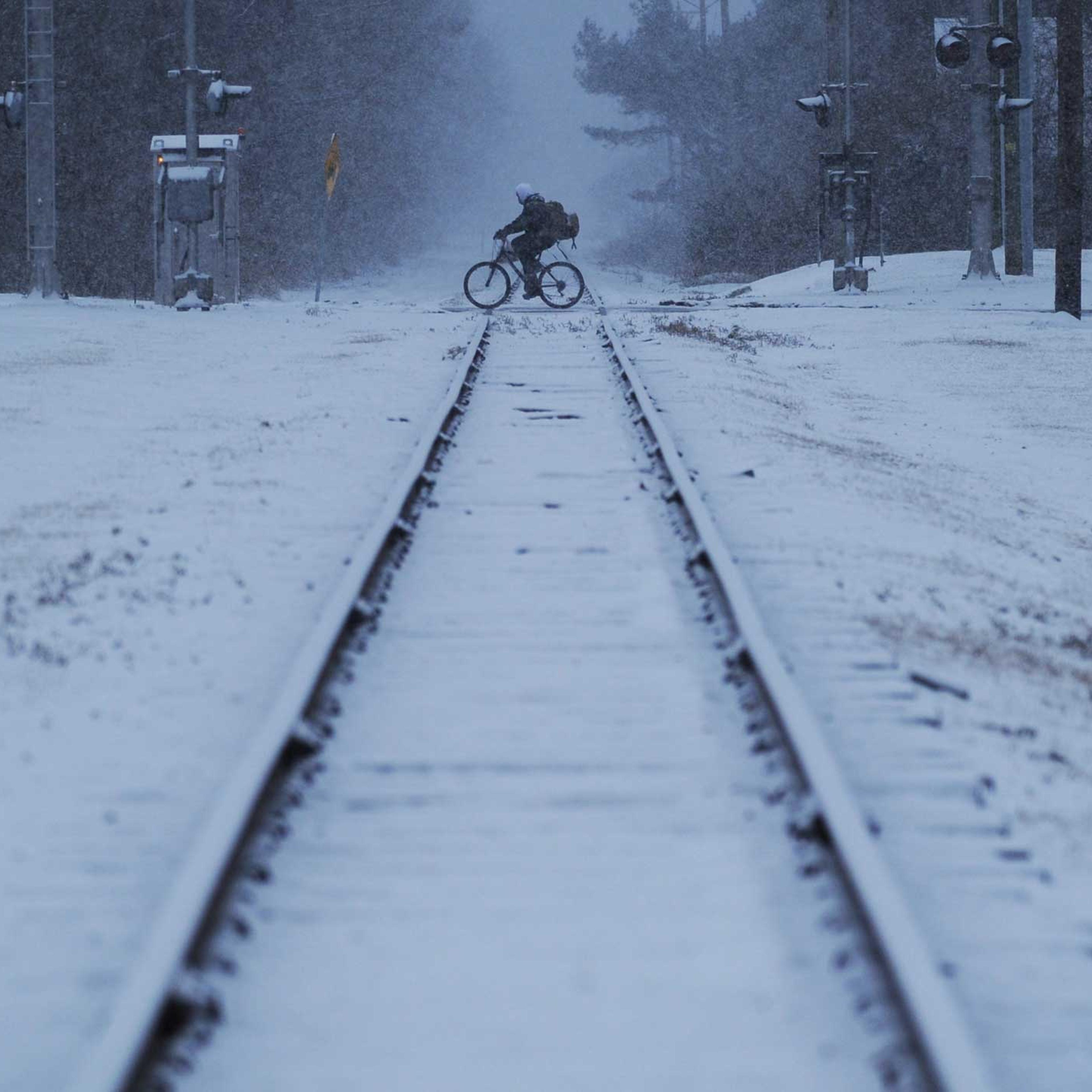 A man rides his bicycle across the railroad tracks in Exmore, Va. as snow falls, Feb. 24, 2015.