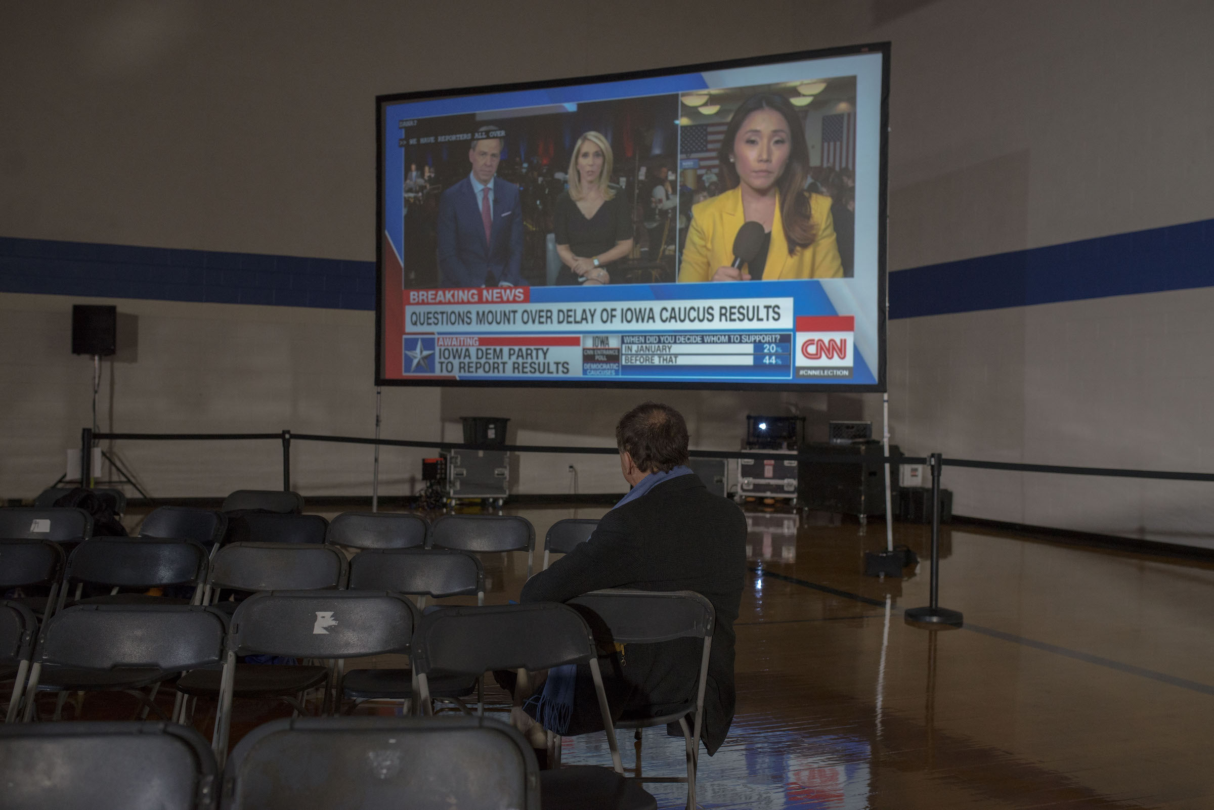 An attendee at an Iowa Caucus watches the news on Caucus Day in Des Moines, Iowa on Feb. 3, 2020.