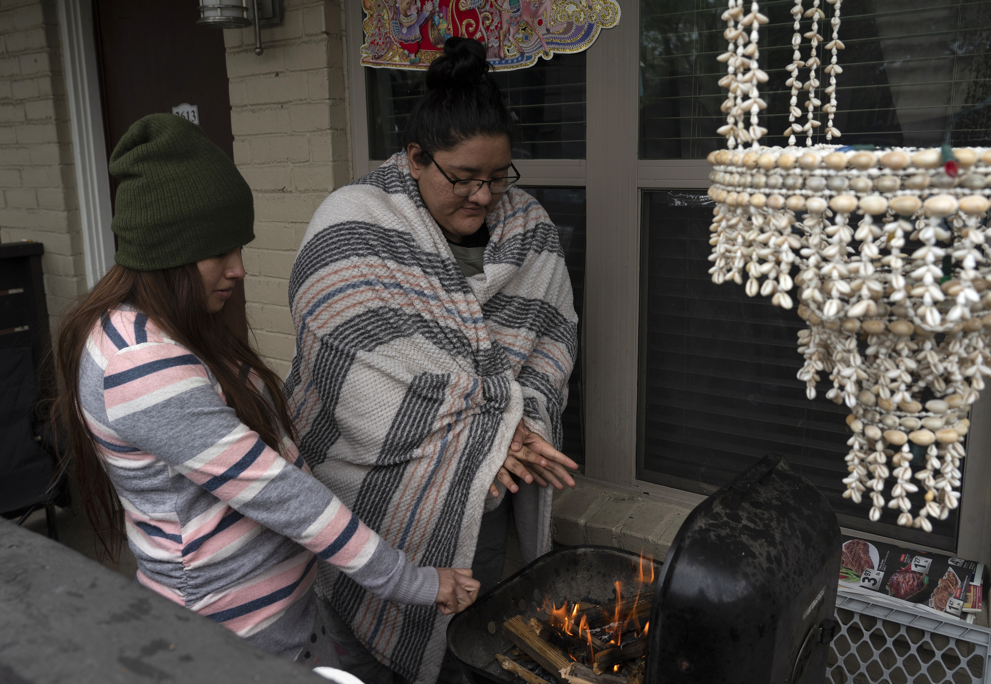 Karla Perez and Esperanza Gonzalez warm up by a barbecue grill during power outage caused by the winter storm on February 16, 2021 in Houston, Texas.