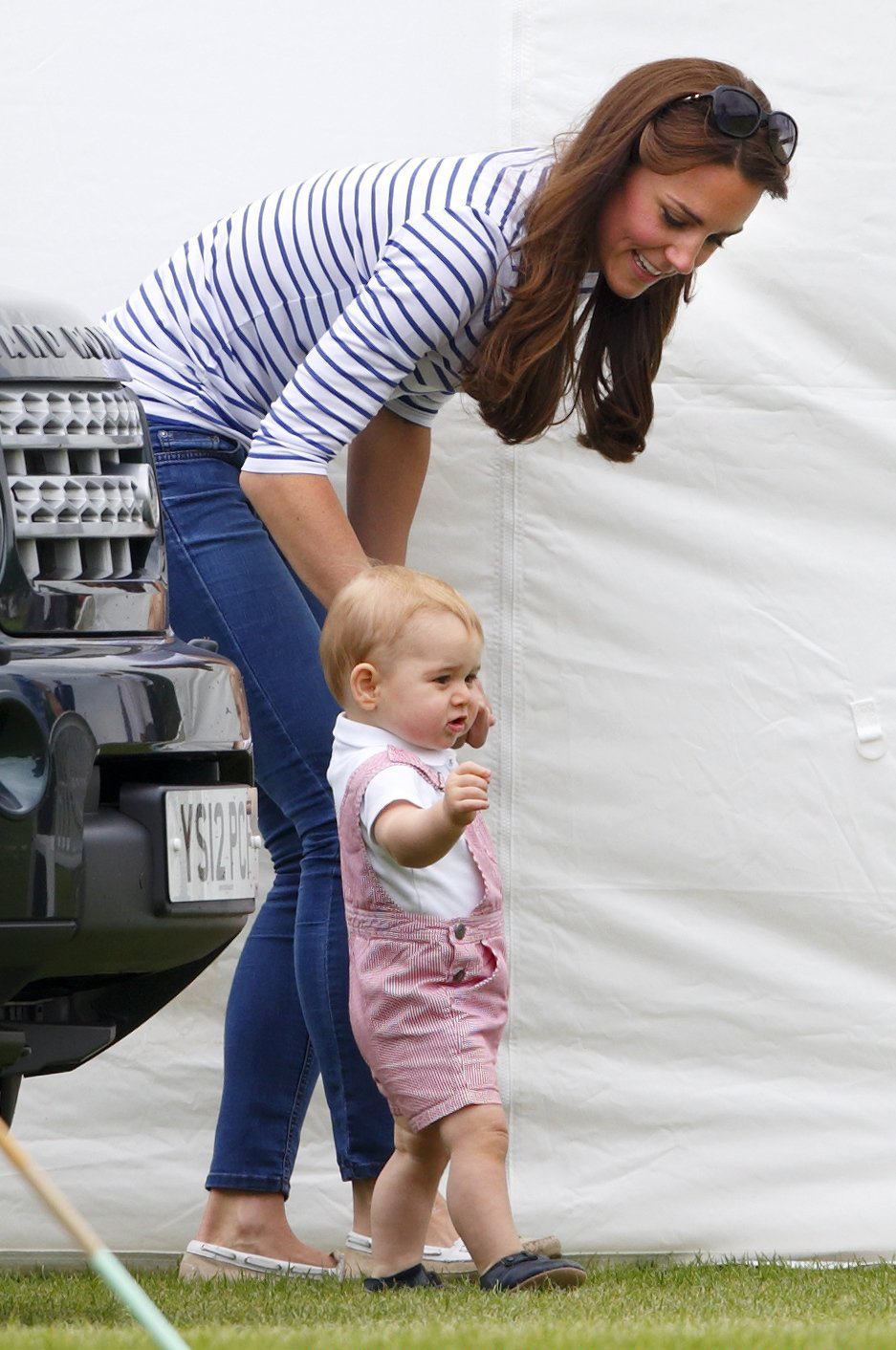 Prince George of Cambridge walks holding his mother Catherine, Duchess of Cambridge's hand as they watch Prince William, Duke of Cambridge and Prince Harry play in the Jerudong Trophy charity polo match at Cirencester Park Polo Club on June 15, 2014 in C