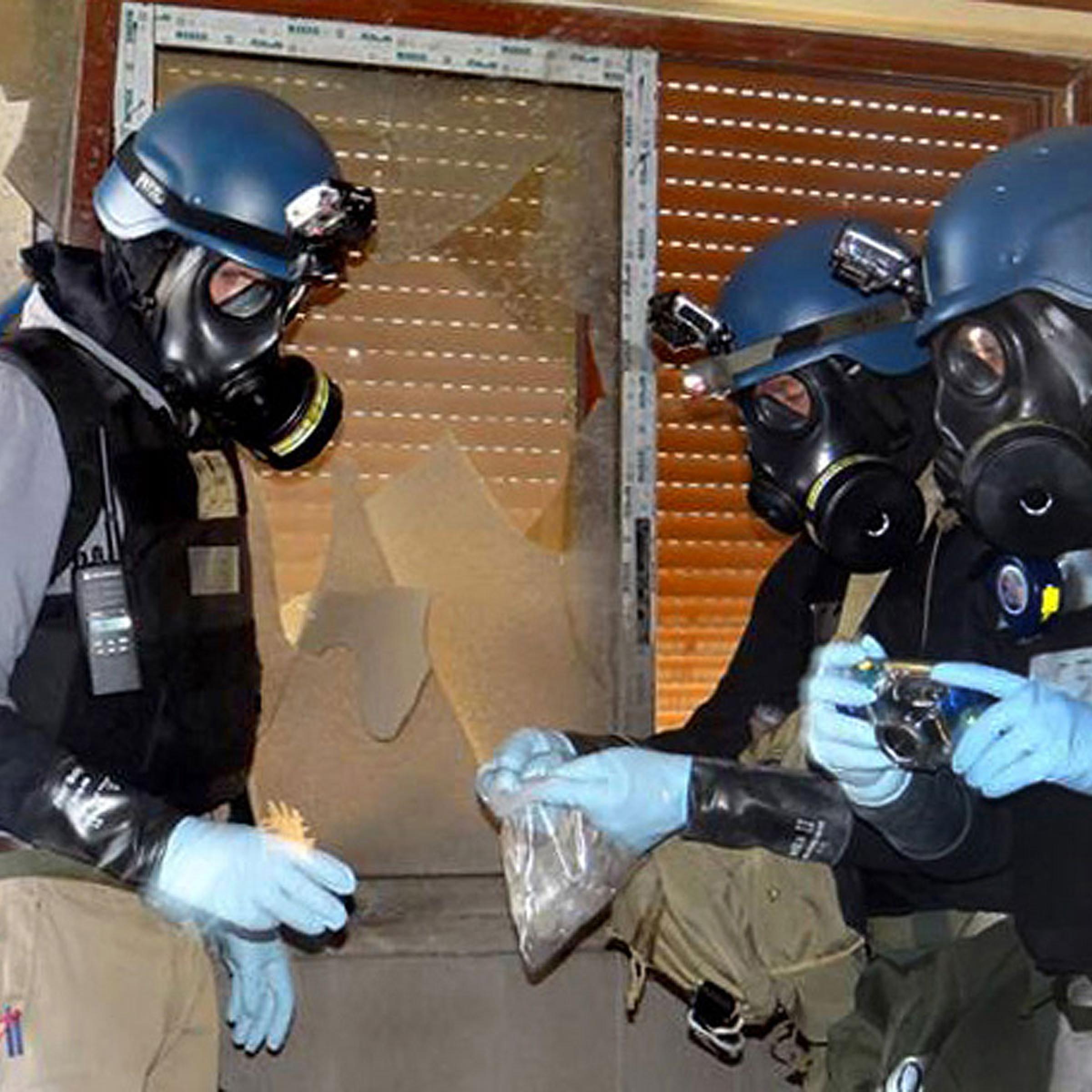In this Thursday, Aug. 29, 2013 file citizen journalism image provided by the Local Committee of Arbeen which has been authenticated based on its contents and other AP reporting, members of the UN investigation team take samples from the ground in the Damascus countryside of Zamalka, Syria