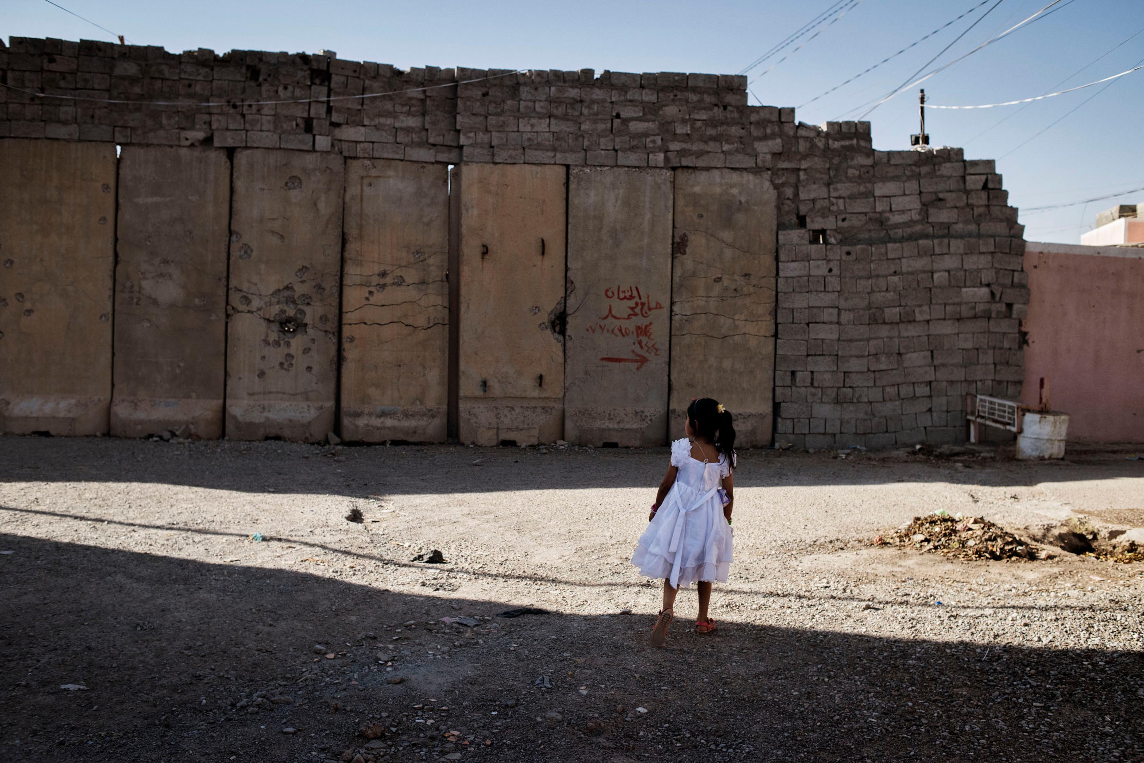 A young girl walks by a wall in the town of Tuz Khurmatu, northern Iraq, May 20, 2016. Walls have been installed in the city as a result of recent fighting between rival Kurdish and Shiite Turkmen factions. The deadly clashes signaled tension among among