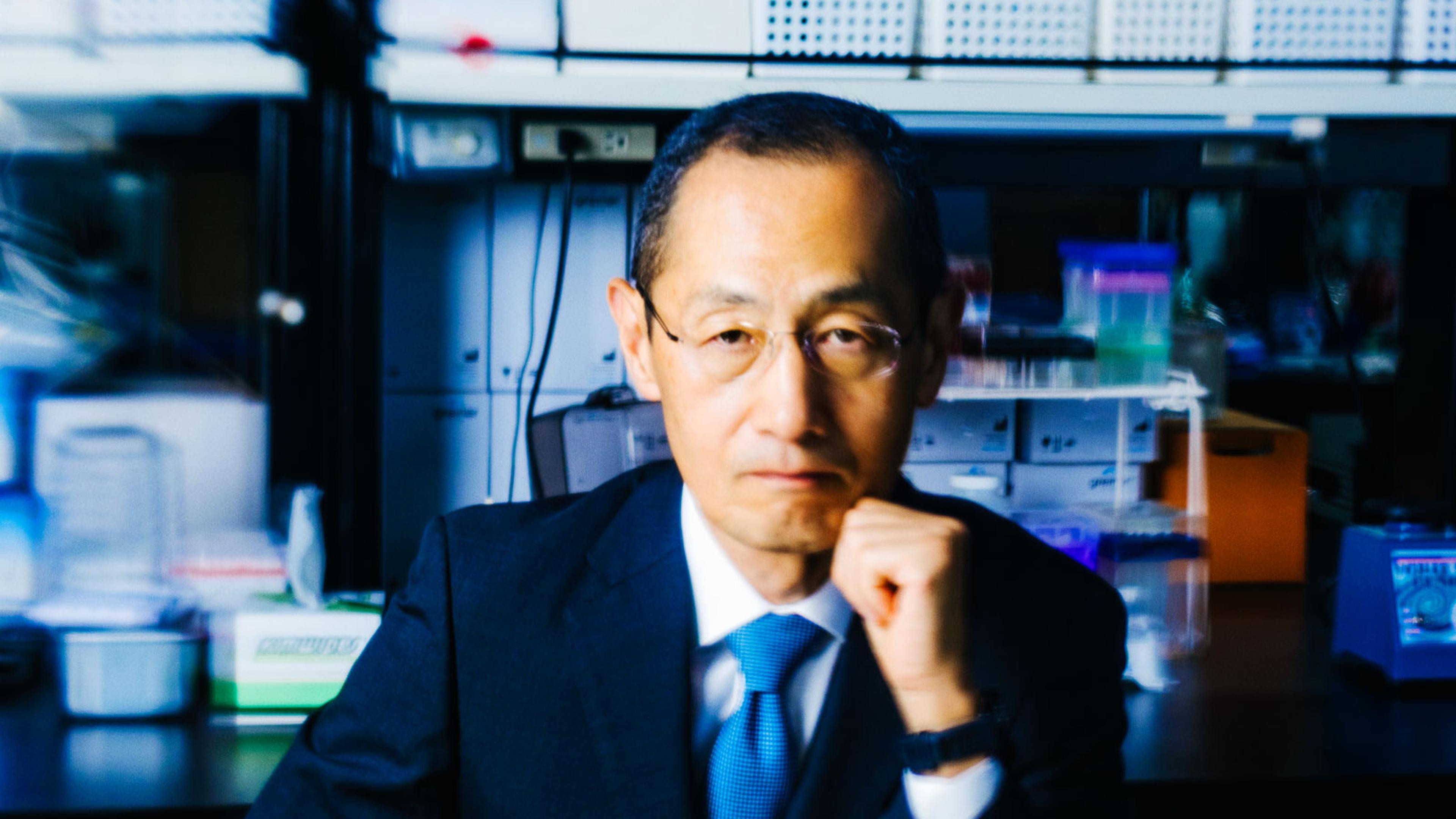Shinya Yamanaka in a laboratory setting discussing research with colleagues.