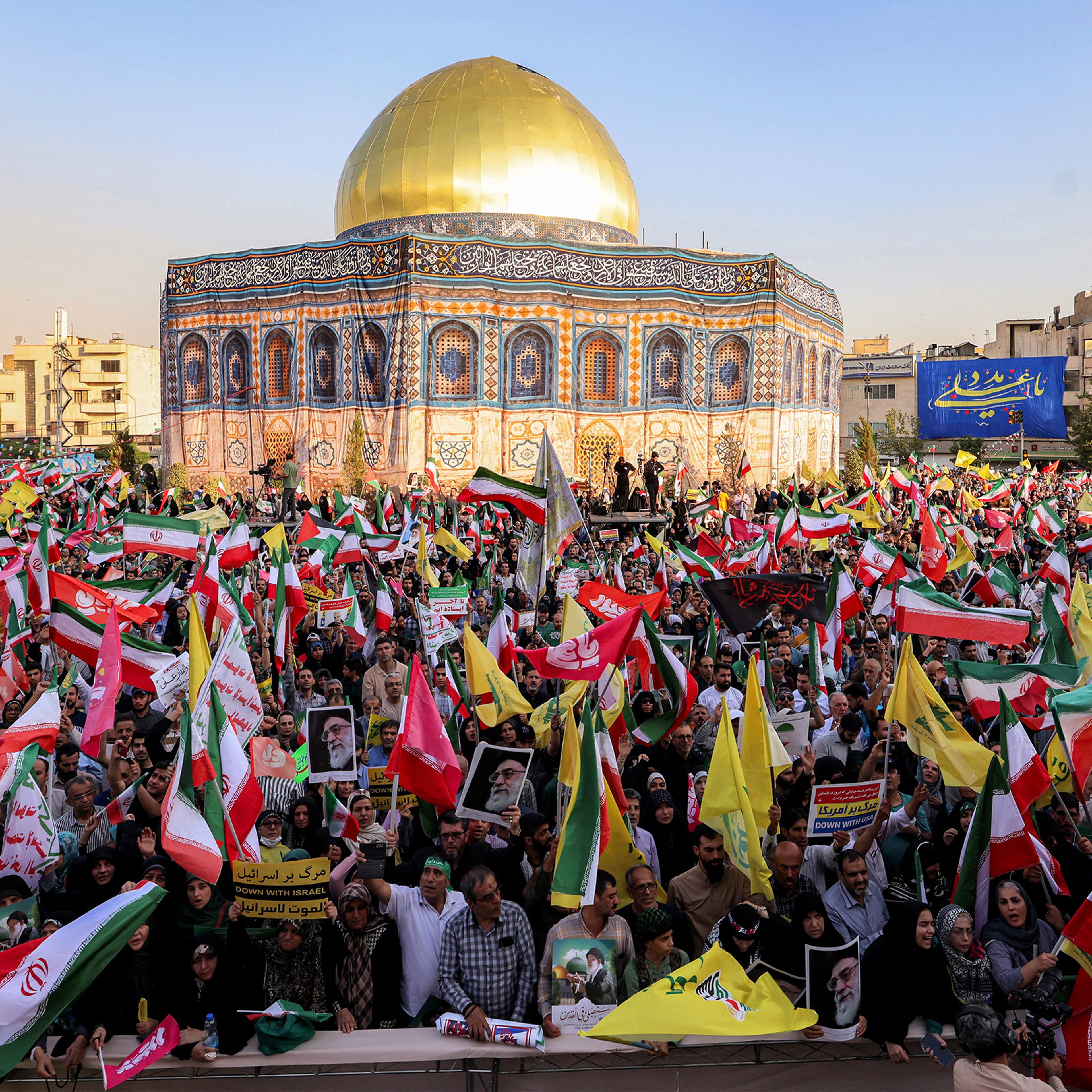 Demonstrators wave flags as they gather before a mockup of Jerusalem's Dome of the Rock during a rally in solidarity with the government against Israel's attacks on Iran in Tehran on June 14, 2025.