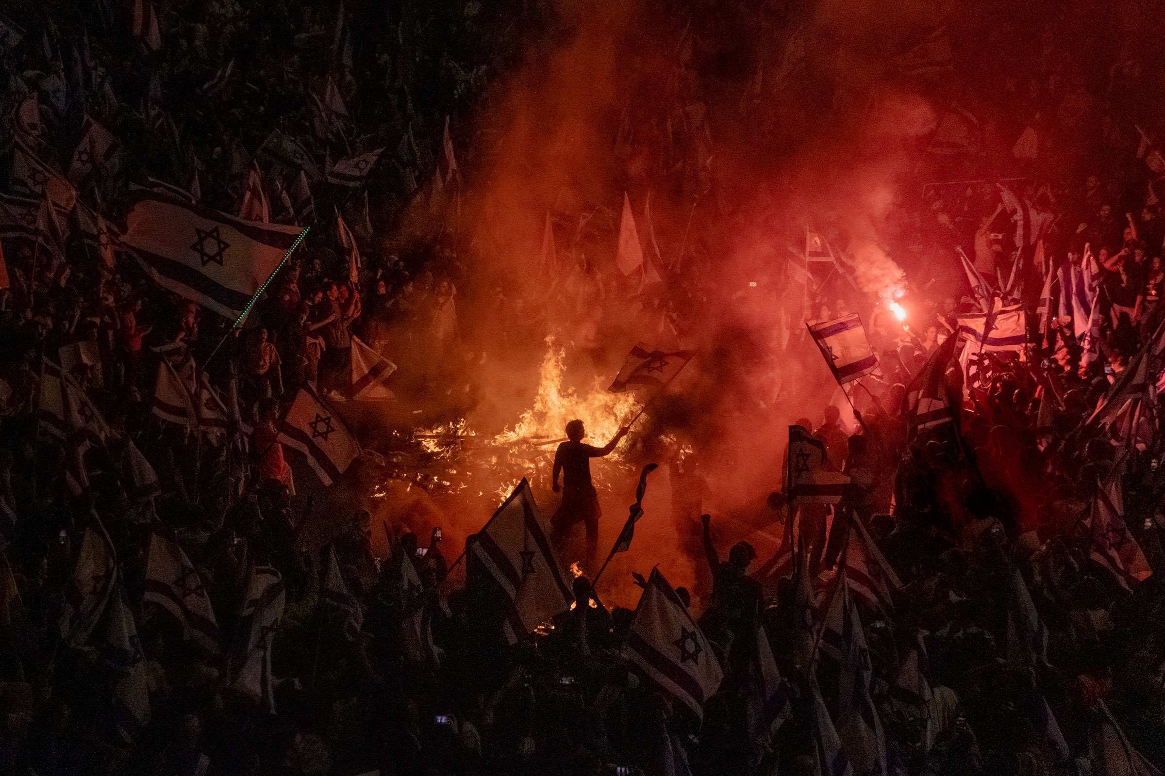 Israelis opposed to Prime Minister Benjamin Netanyahu's judicial overhaul plan set up bonfires, firecrackers and block a busy highway during a protest in Tel Aviv, moments after the Israeli leader fired his defense minister, on March 26.