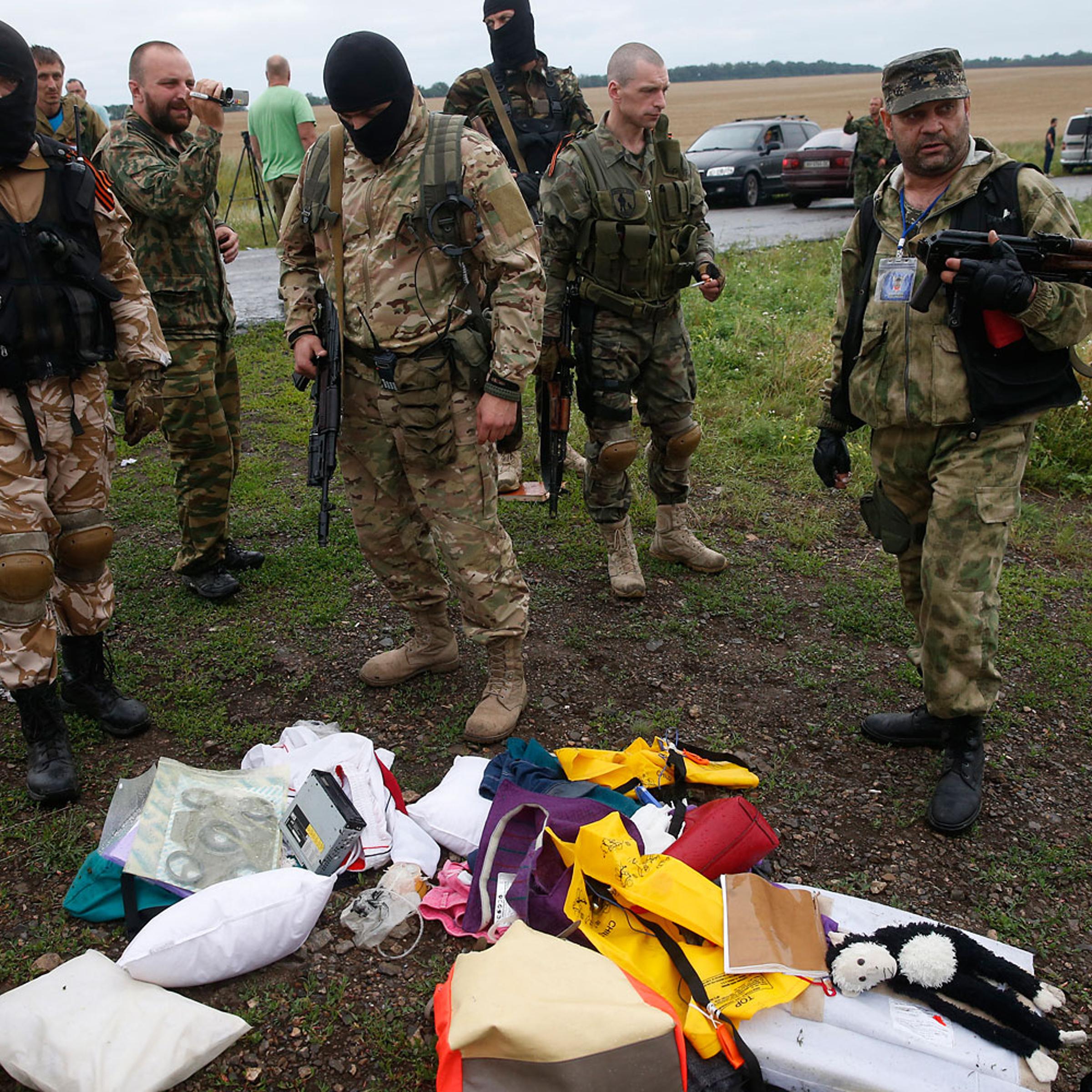 Pro-Russian separatists look at passengers' belongings at the crash site of Malaysia Airlines flight MH17, near the settlement of Grabovo in the Donetsk region