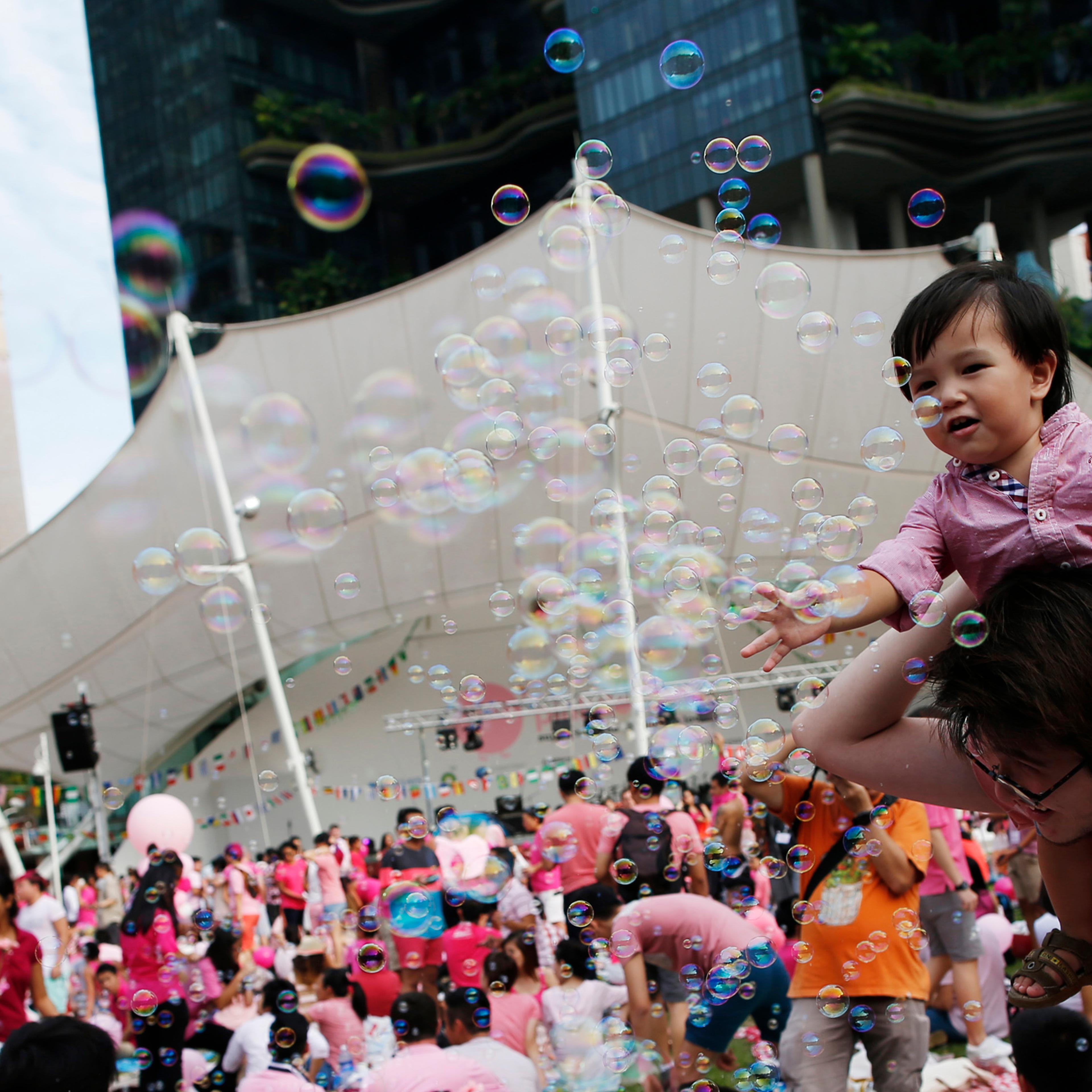 Toddler plays with bubbles as participants wait to take part in the forming of a giant pink dot at the Speakers' Corner in Hong Lim Park in Singapore