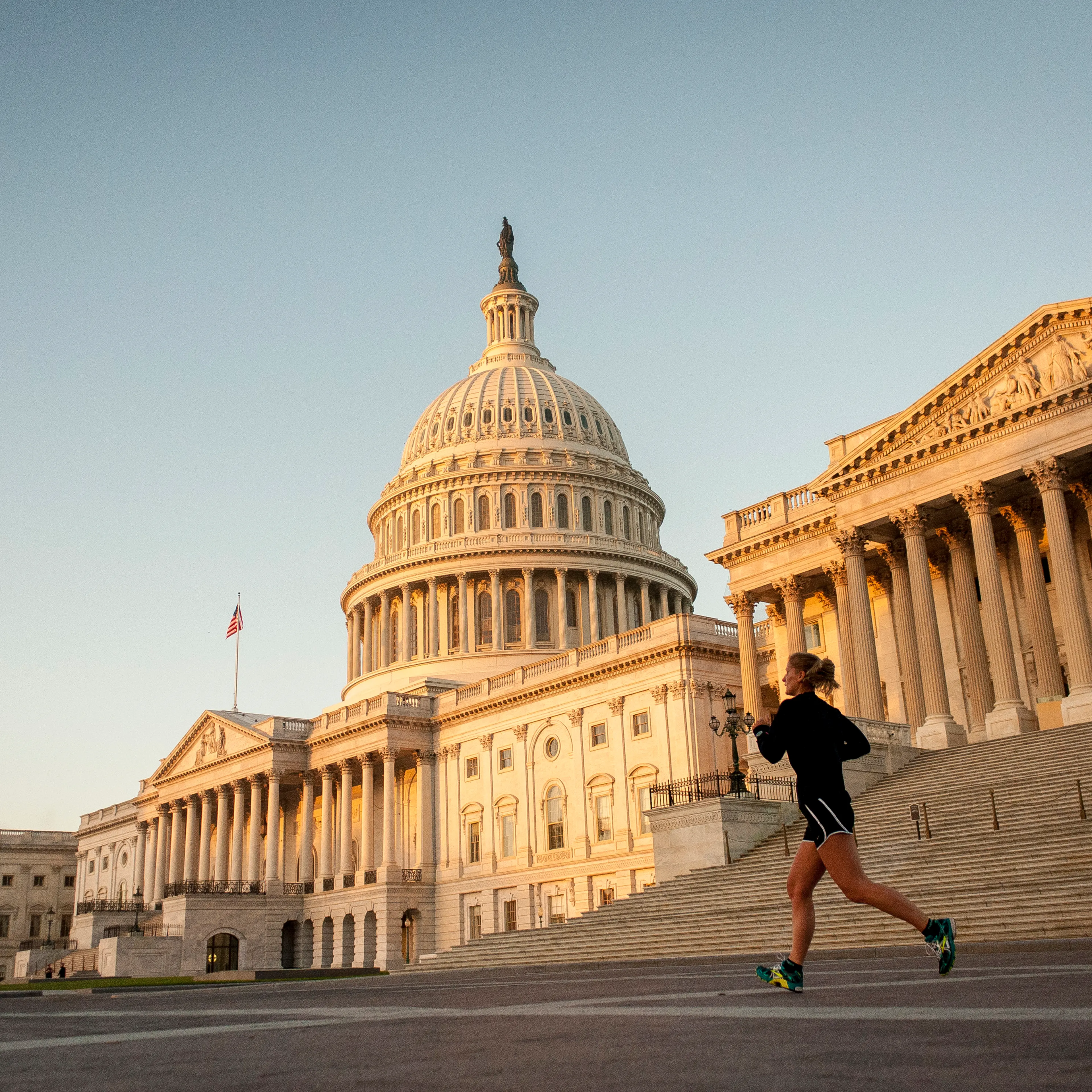 A jogger runs past the United States Capitol building at sunrise in Washington, D.C., U.S., on Tuesday, Oct. 15, 2013.