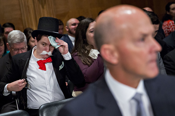A demonstrator sits in costume behind Richard Smith, former CEO of Equifax, before a Senate Banking Committee hearing in Washington, D.C., on Oct. 4, 2017.