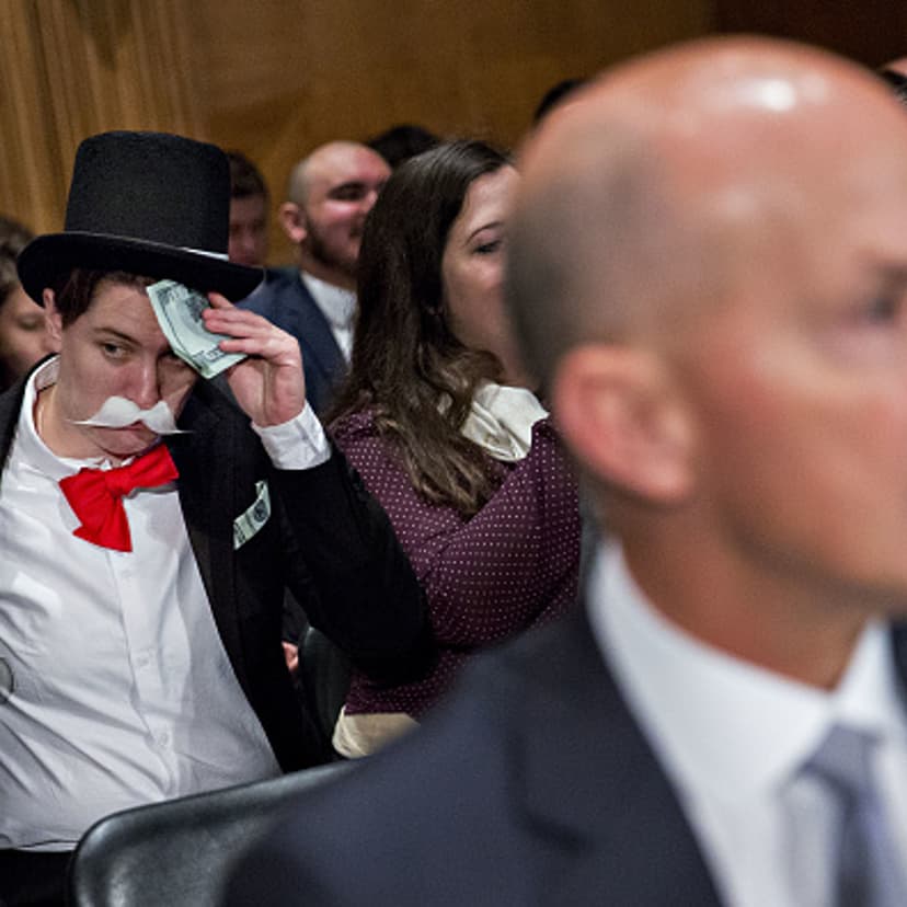 A demonstrator sits in costume behind Richard Smith, former CEO of Equifax, before a Senate Banking Committee hearing in Washington, D.C., on Oct. 4, 2017.