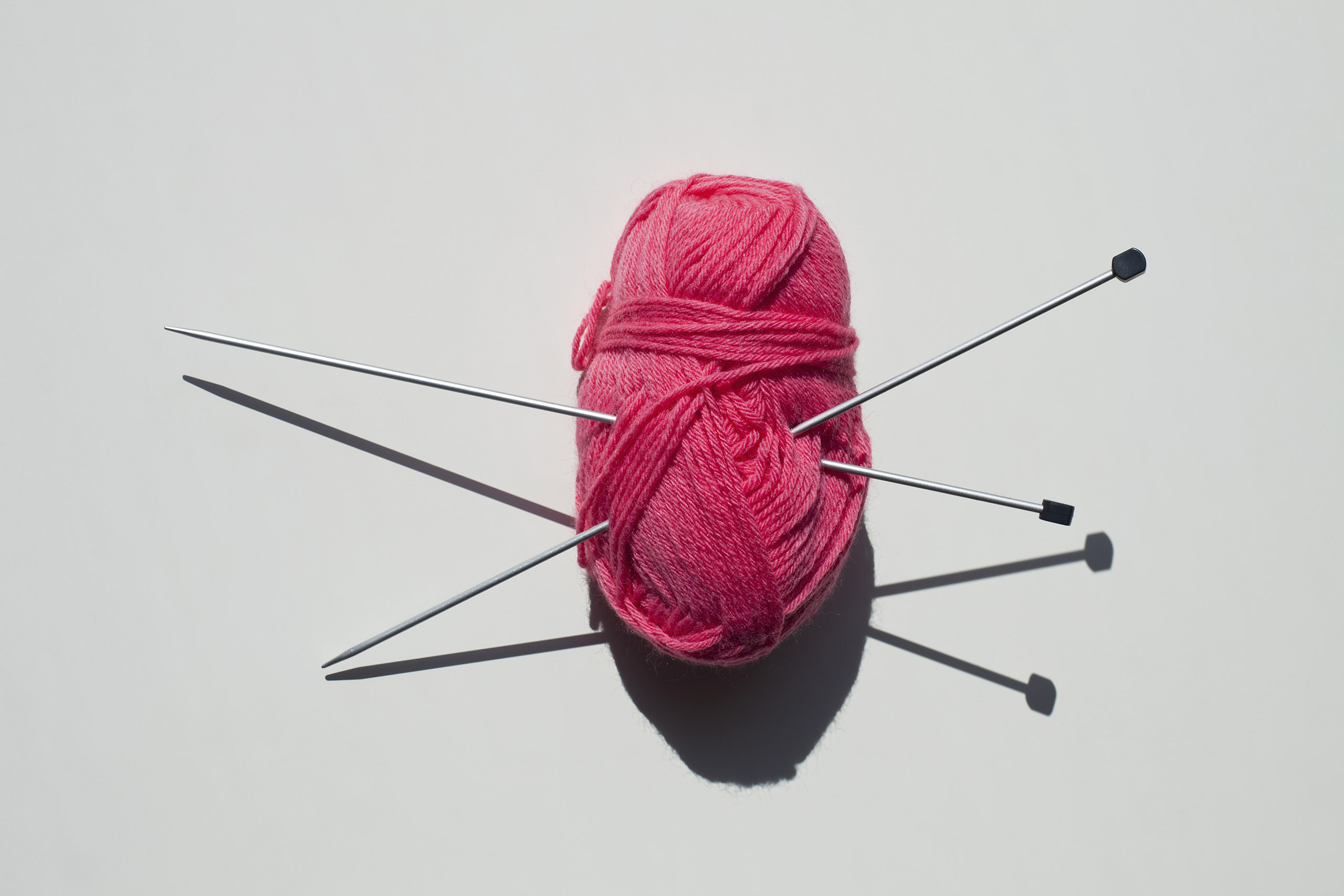 A pair of knitting needles stuck into a ball of yarn