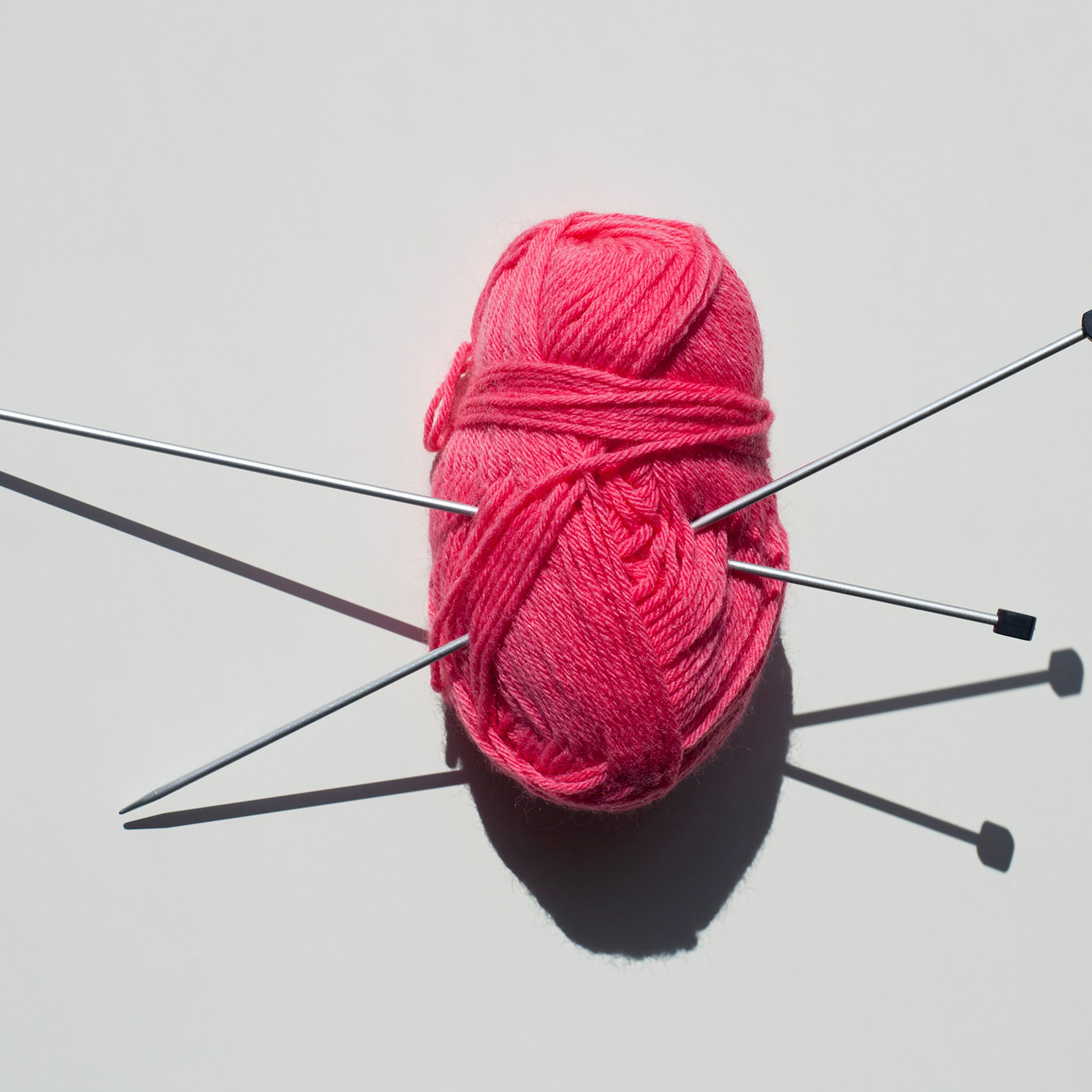 A pair of knitting needles stuck into a ball of yarn
