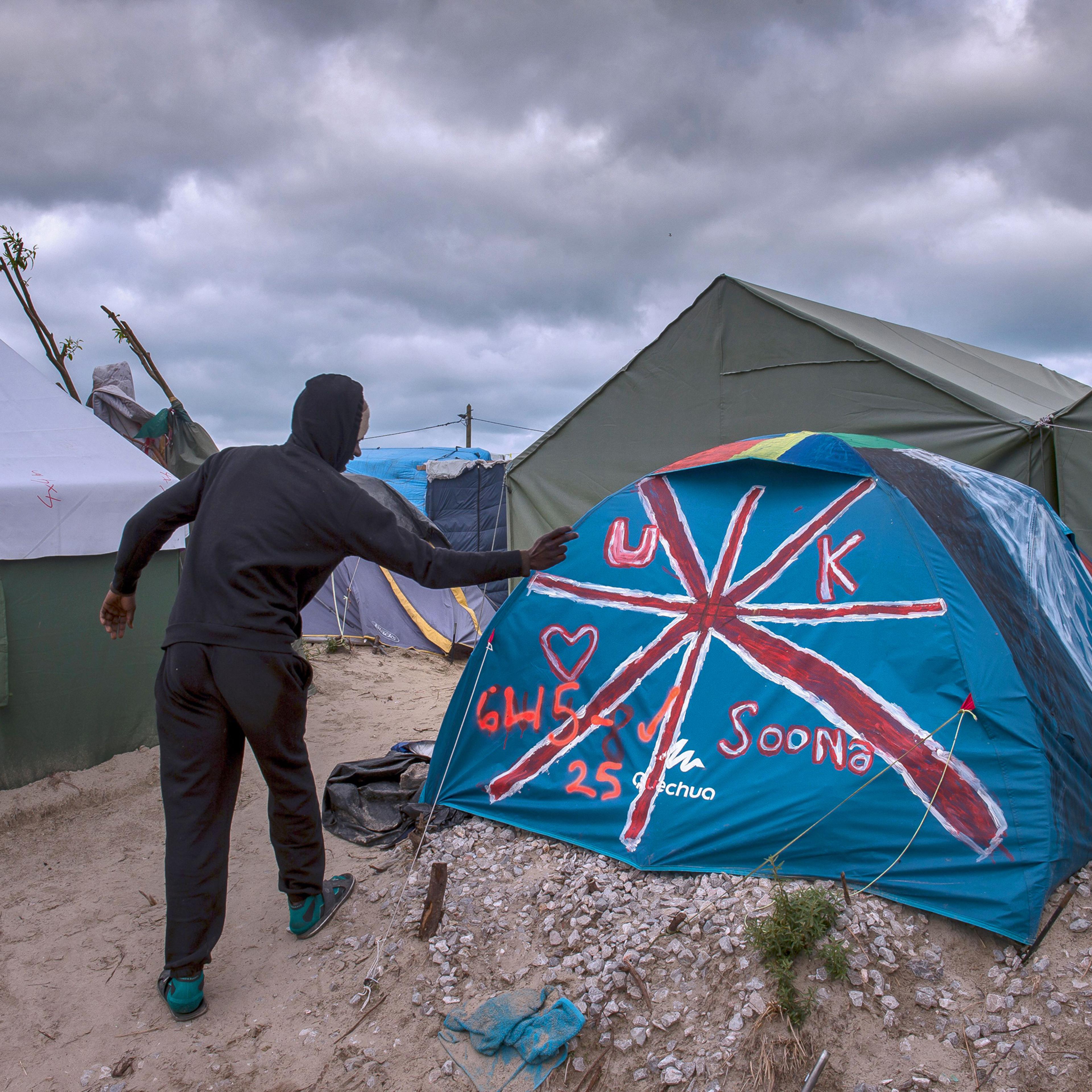 A Sudanese man stands near a tent painted with the British flag at the "Jungle" migrant camp in Calais on Oct. 12, 2016.