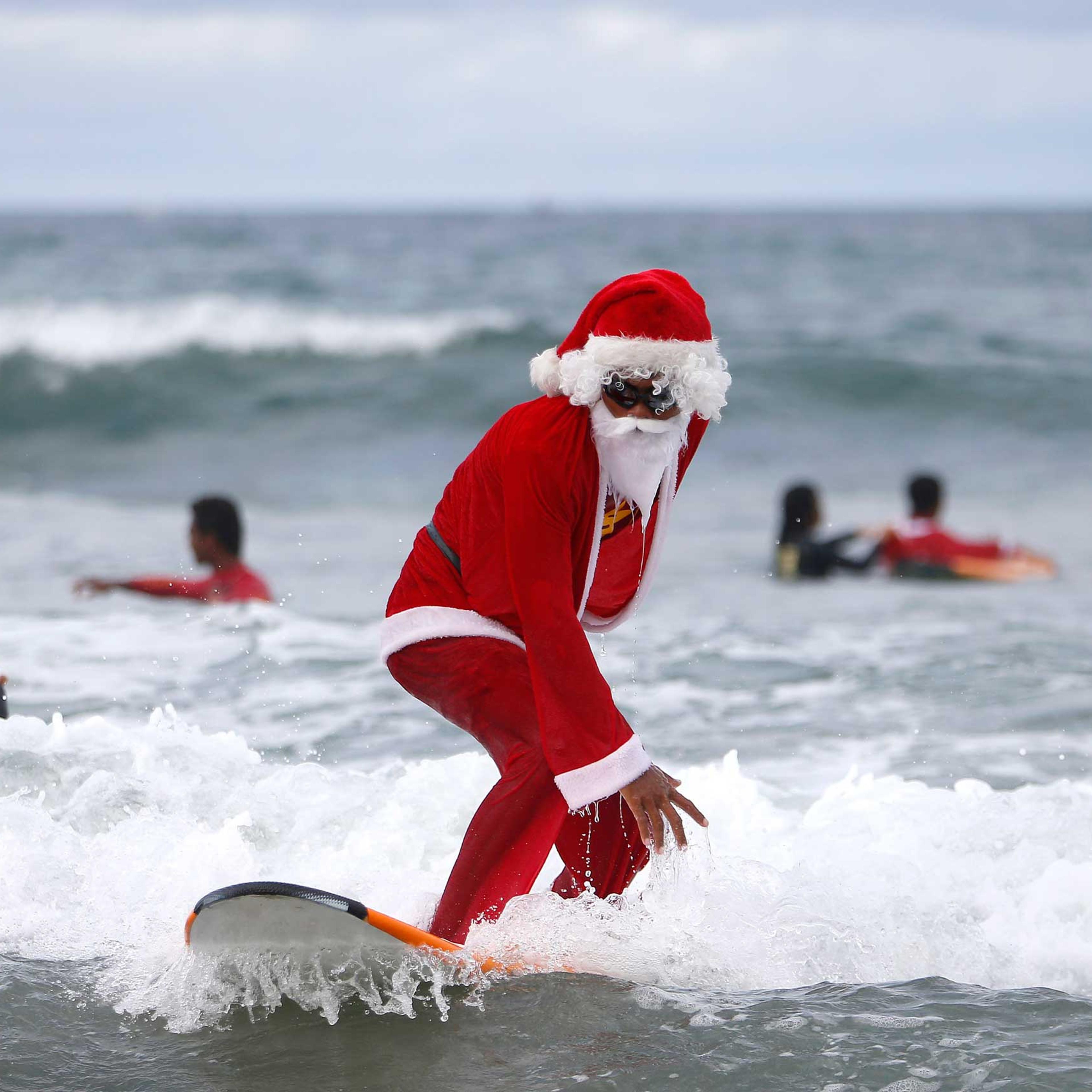A Balinese man dressed as Santa Claus teaches orphan children how to surf at a beach in Bali, Indonesia on Dec. 7, 2014.