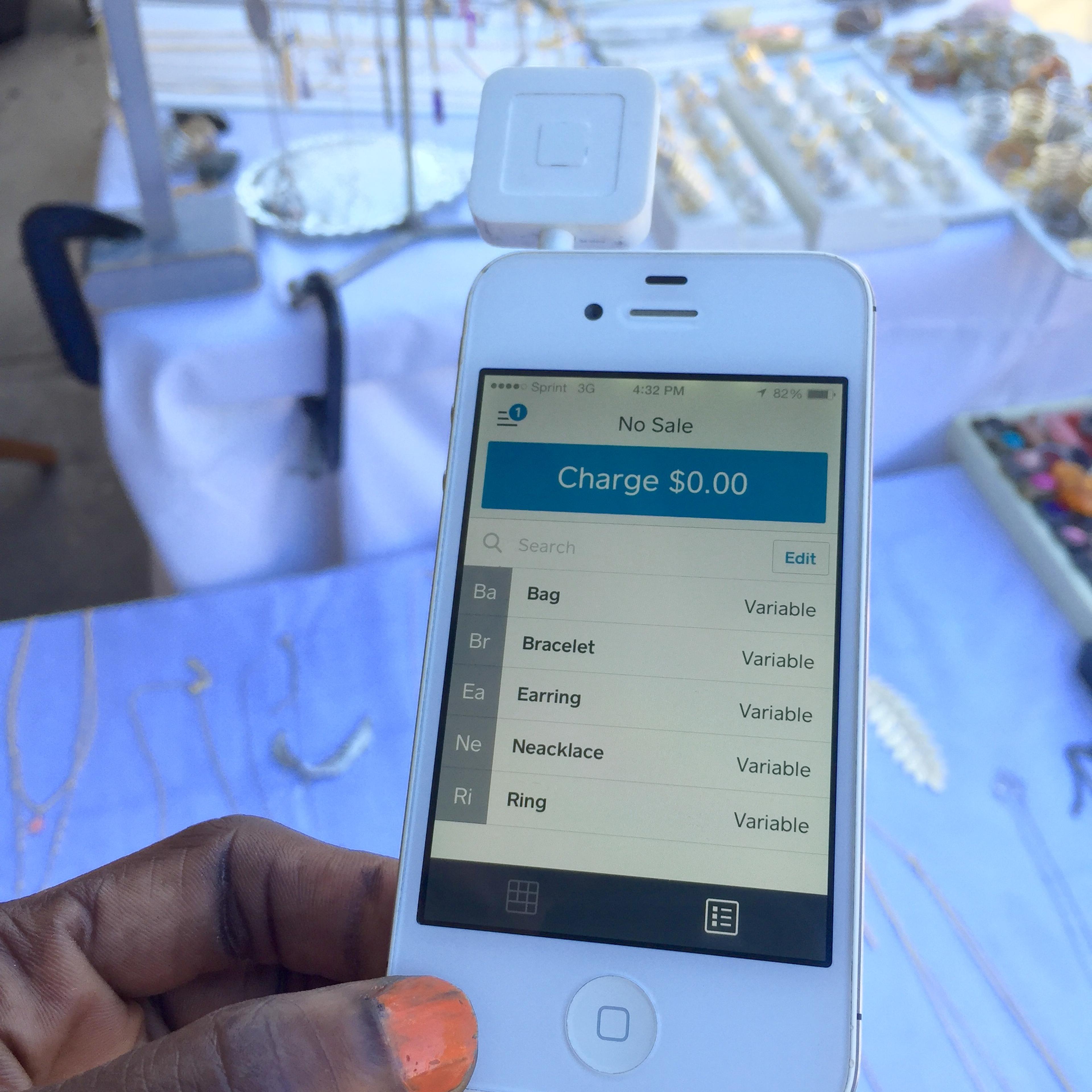 Technology Helps: A jewelry vendor at an outdoors craft market holds her credit card reader attached to a smart device for mobile point of sales activity