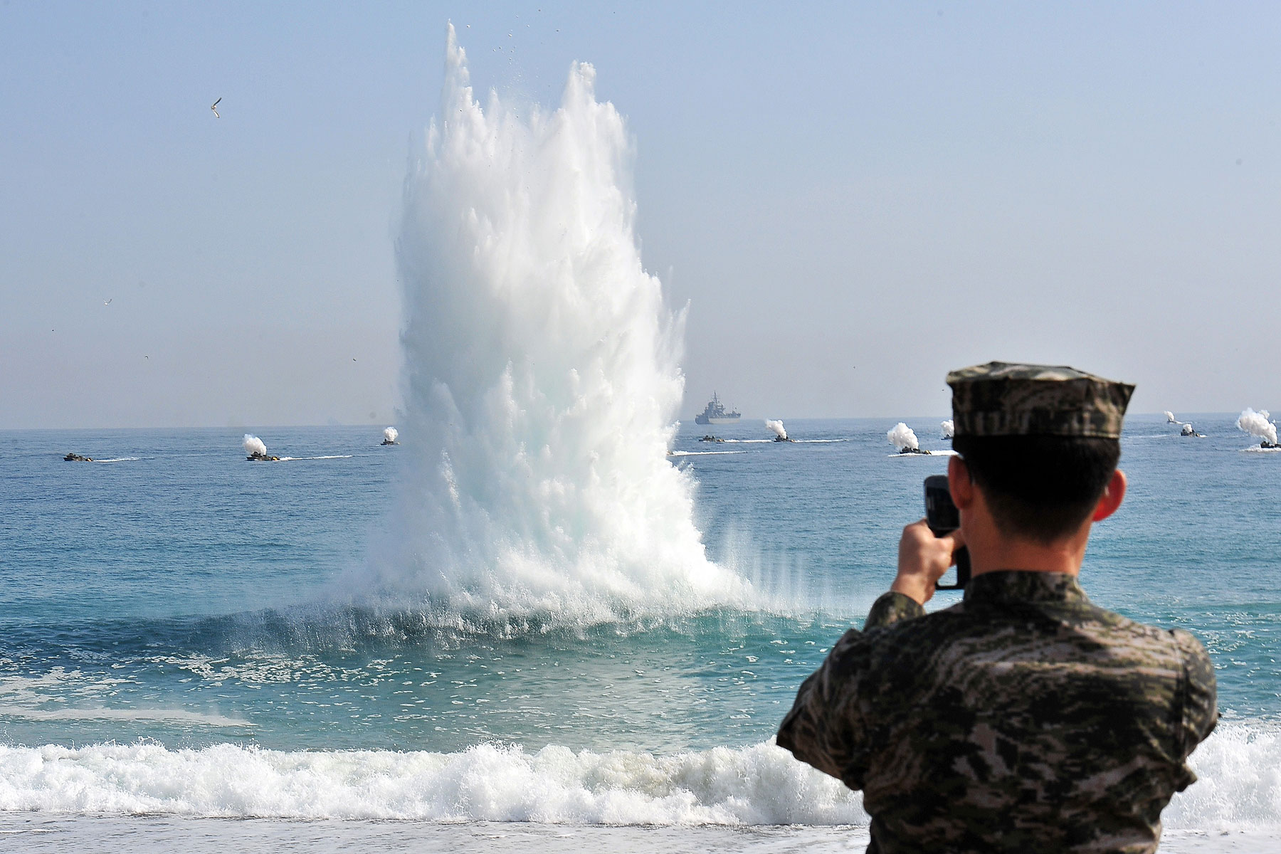 A South Korean Marine stands on a beach as amphibious assault vehicles (in background) approach the seashore during a joint landing operation by US and South Korean Marines in Pohang, 270 kms southeast of Seoul, on March 31, 2014