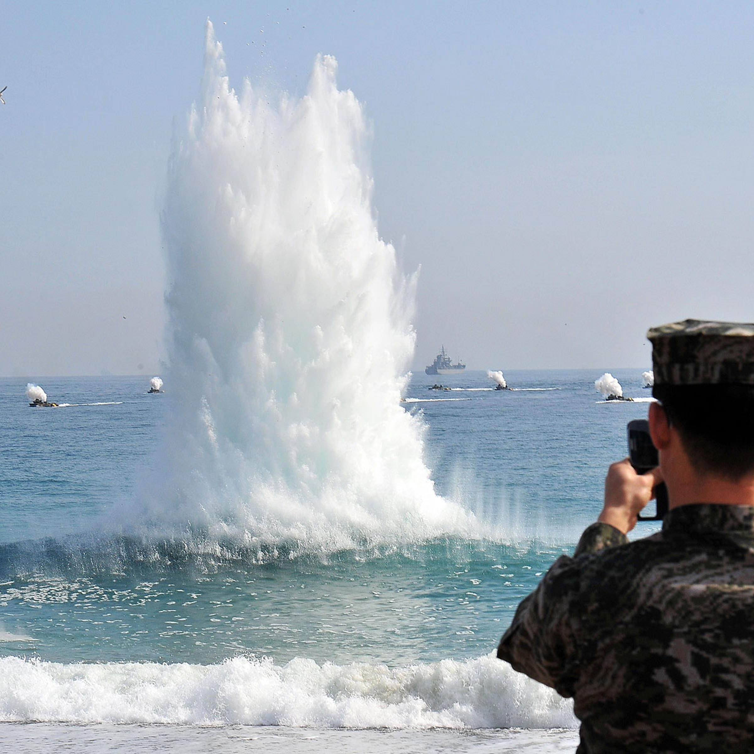 A South Korean Marine stands on a beach as amphibious assault vehicles (in background) approach the seashore during a joint landing operation by US and South Korean Marines in Pohang, 270 kms southeast of Seoul, on March 31, 2014