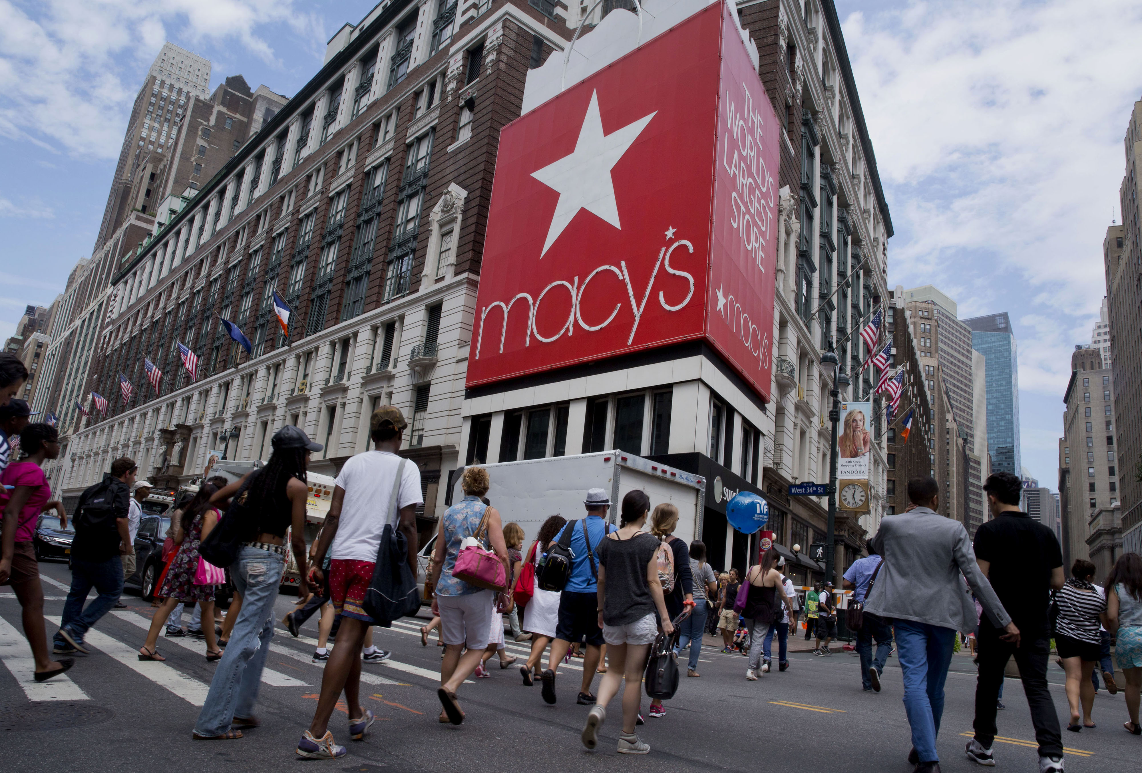 Pedestrians cross the street in front of the Macy's Inc. flagship store in New York City on Aug. 6, 2014.